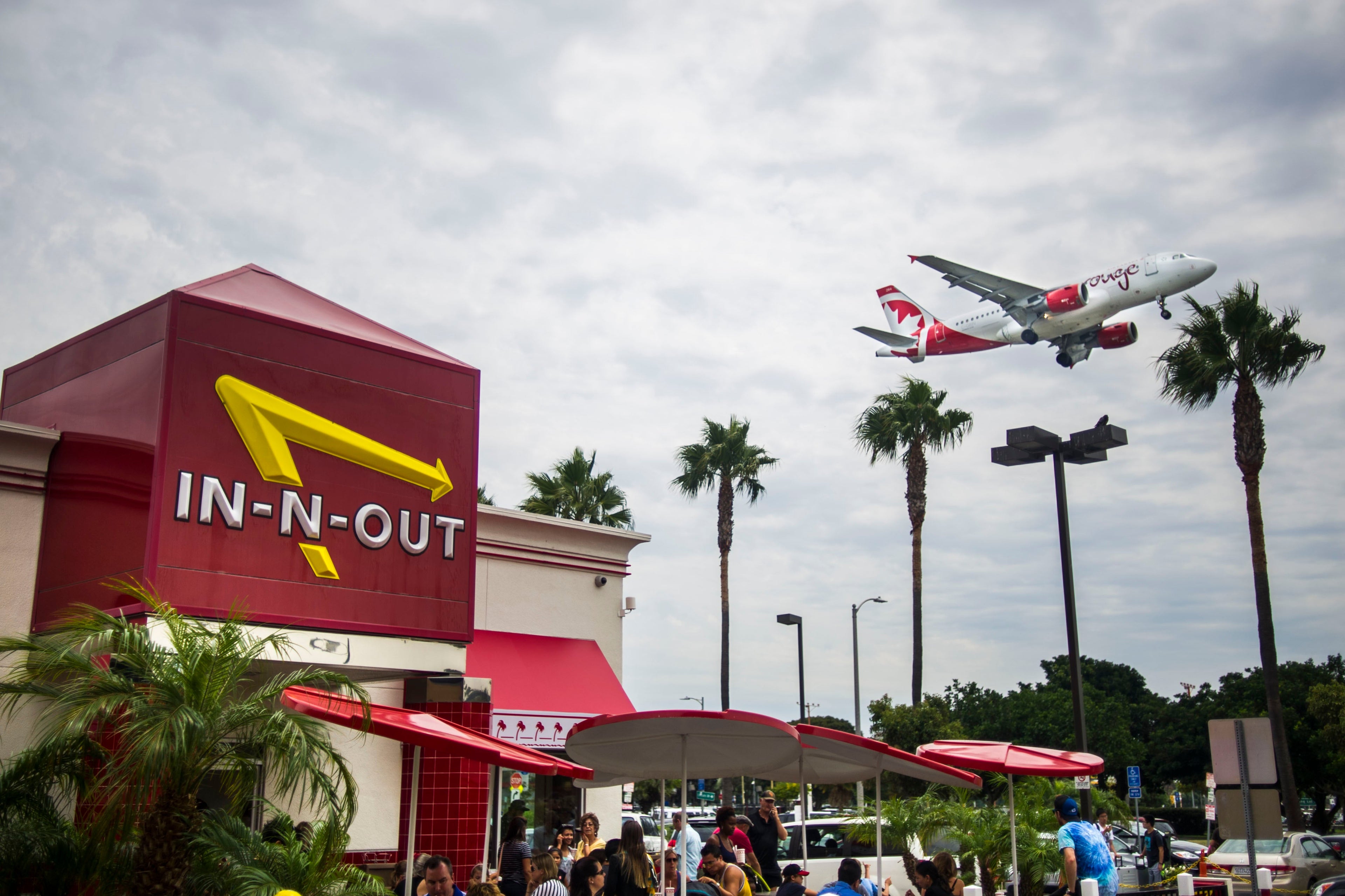 LOS ANGELES, CA - AUGUST 02: An Air Canada Rouge flight is seen above the In-N-Out Burger restaurant Sepulveda Boulevard arriving at Los Angeles International Airport on Saturday, August 02, 2014 in Los Angeles, California. More than 1,500 flights depart and arrive at LAX on a daily basis, ranking it 6th busiest in the world, and 2nd busiest in the United States. (Photo by Kent Nishimura/The Denver Post via Getty Images)