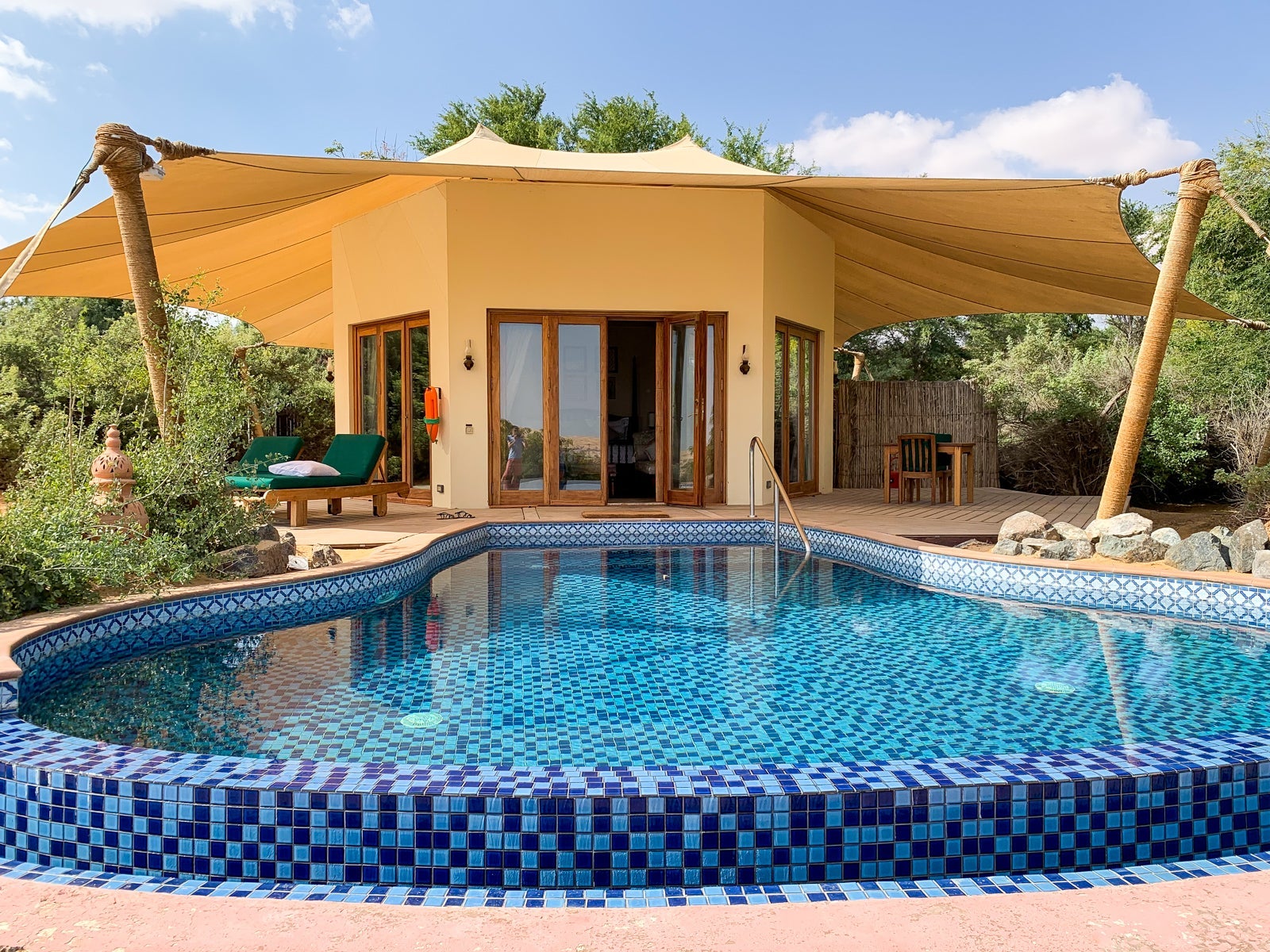a small hut at a hotel sits behind a pool