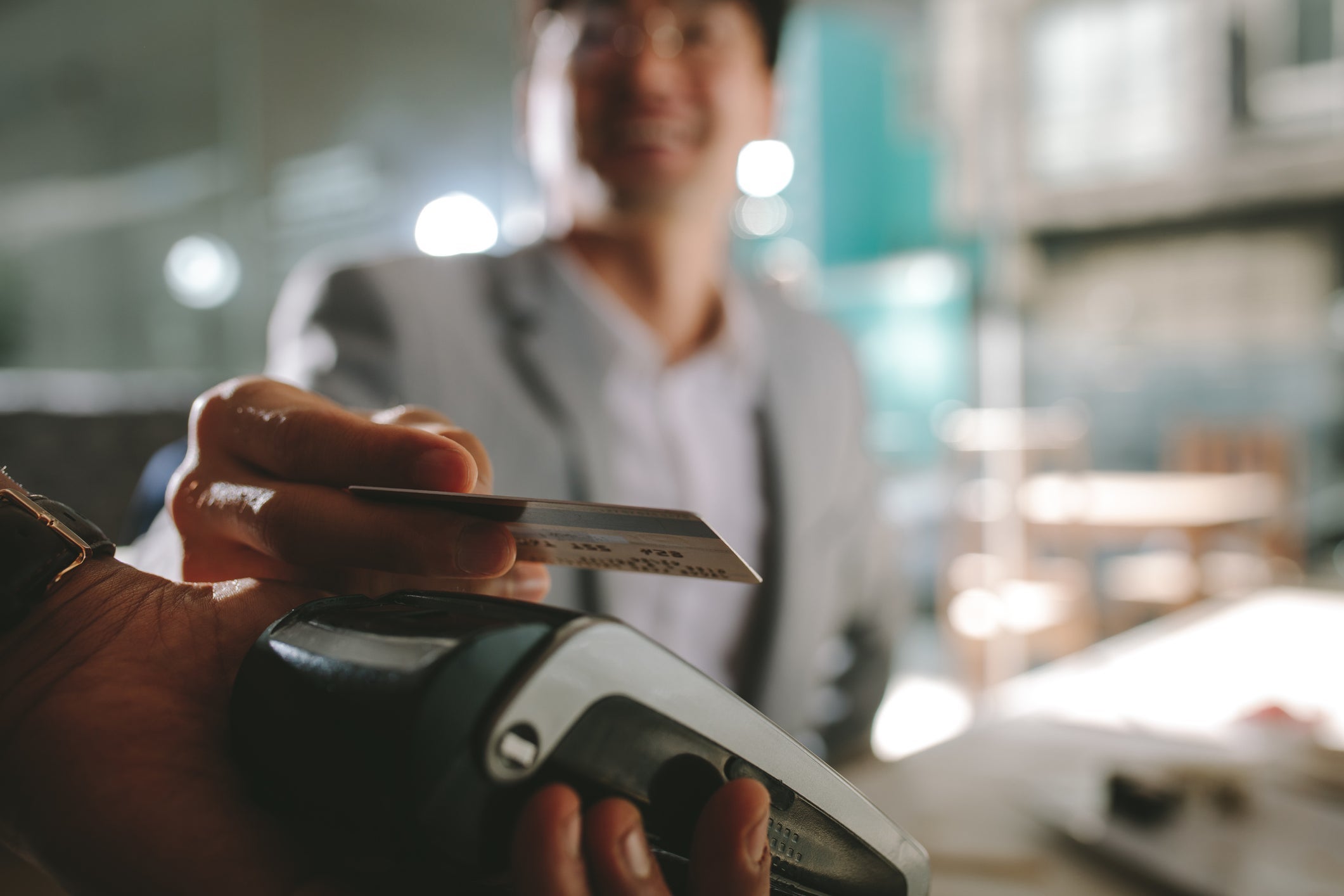 An unseen person taps a credit card on a credit card payment machine