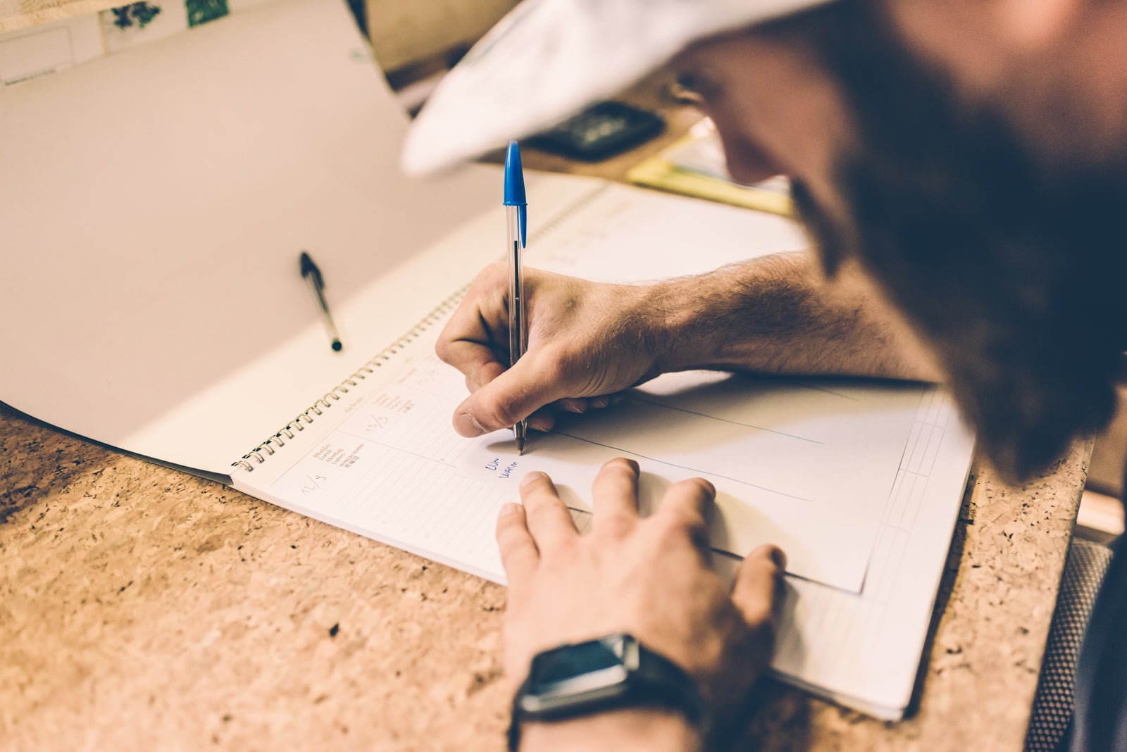 close-up of a man filling out forms with a pen