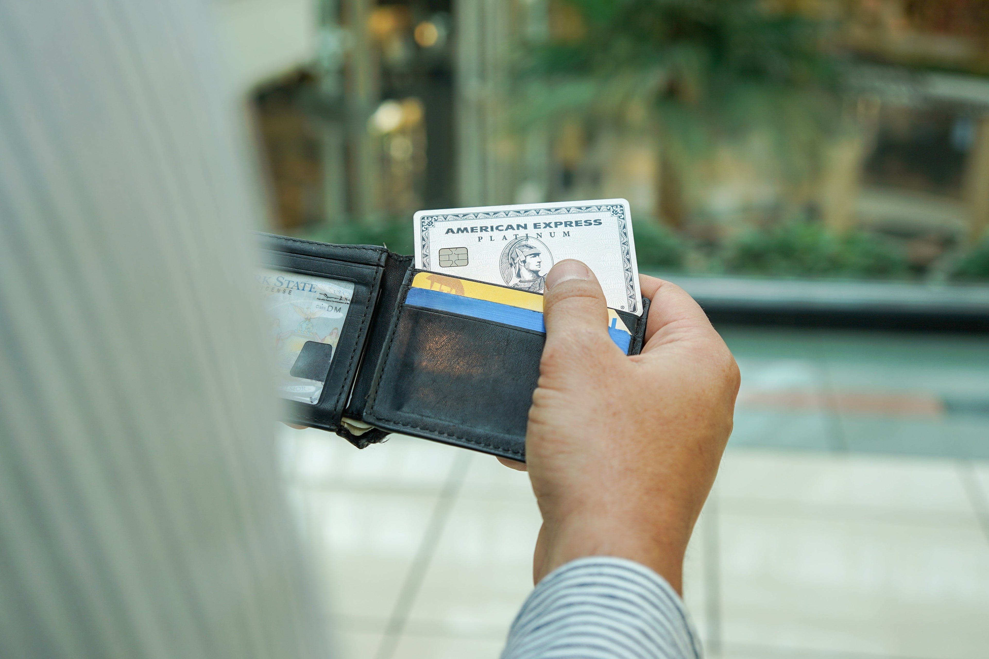 an unseen person pulls an Amex Platinum Card out of a wallet