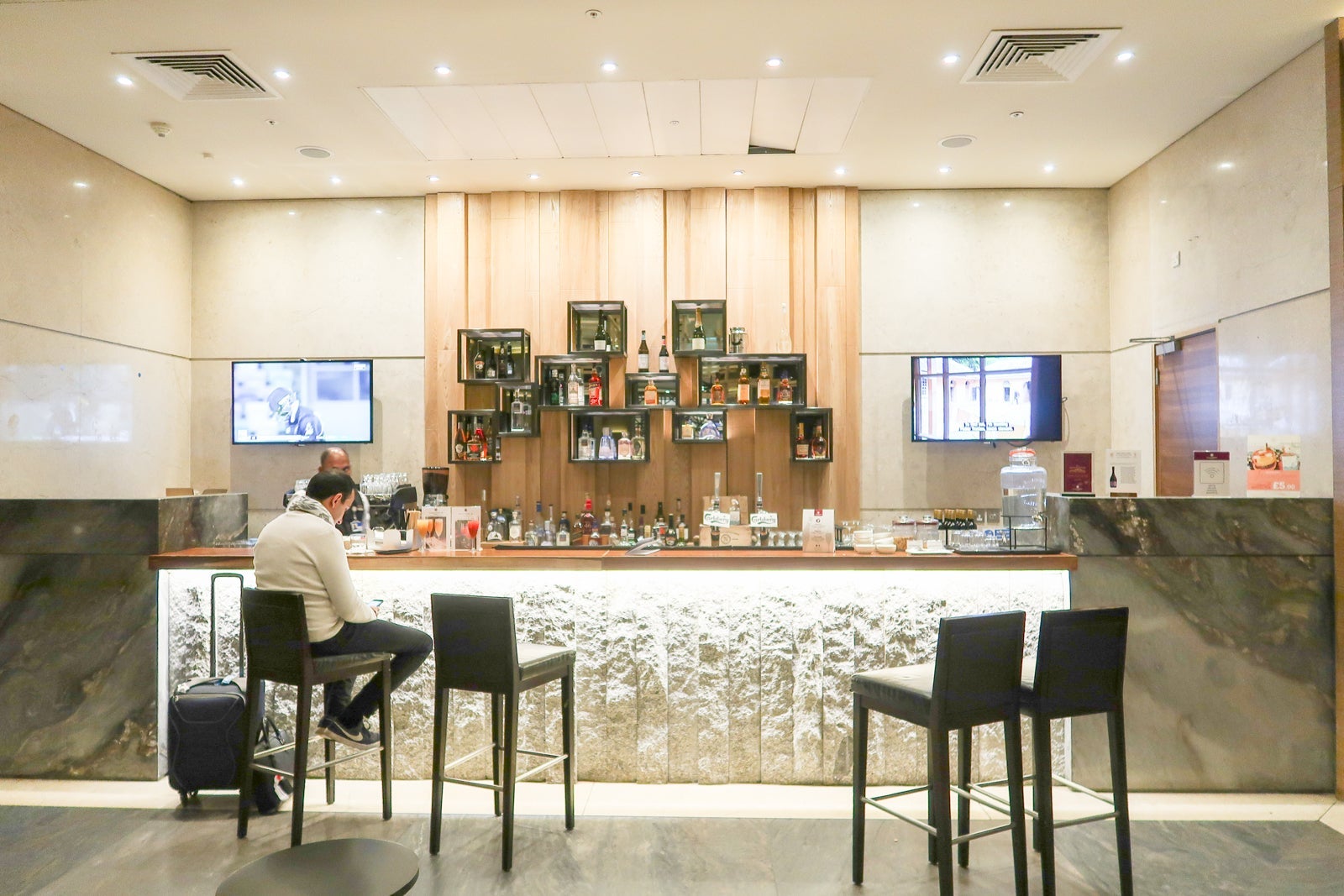 a man checks his phone while sitting at a bar inside an airport lounge
