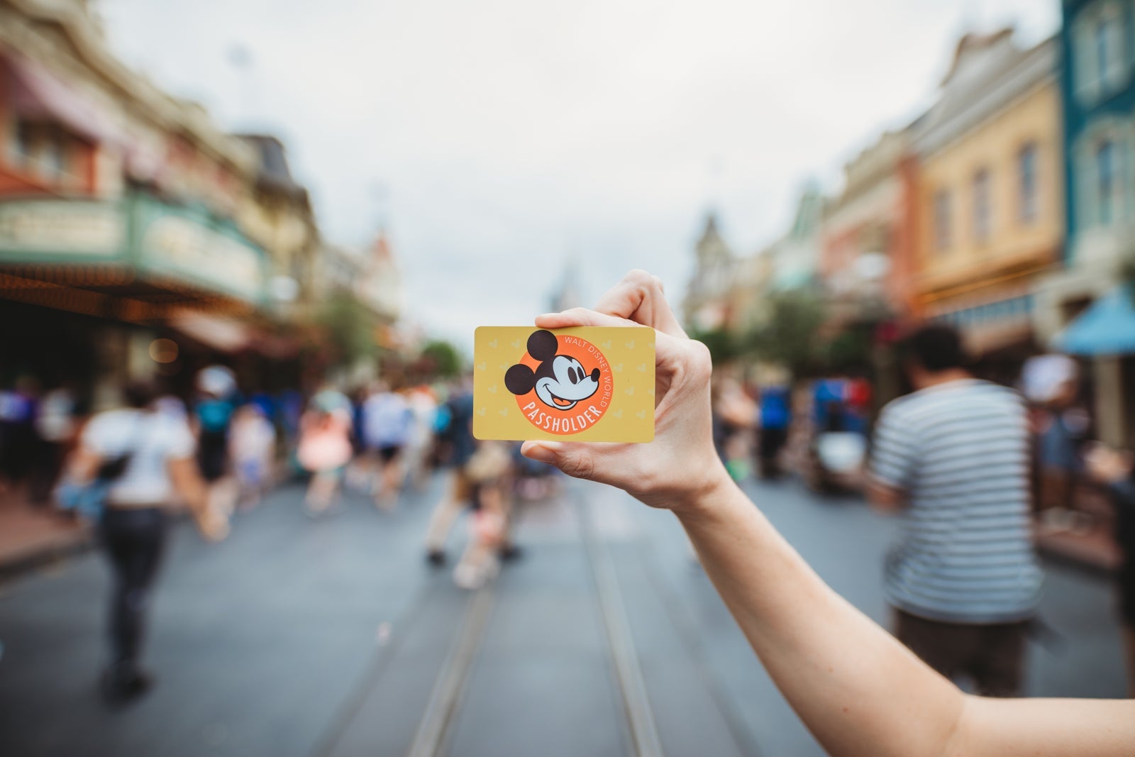 A hand holds up a Disney Annual Pass