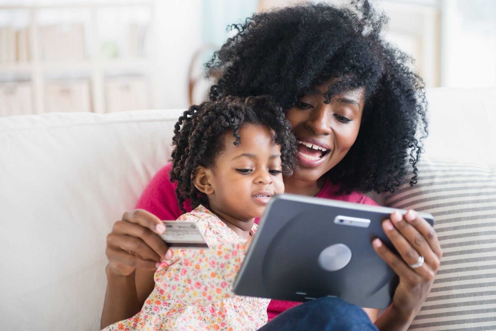 Woman and child sitting on couch using tablet