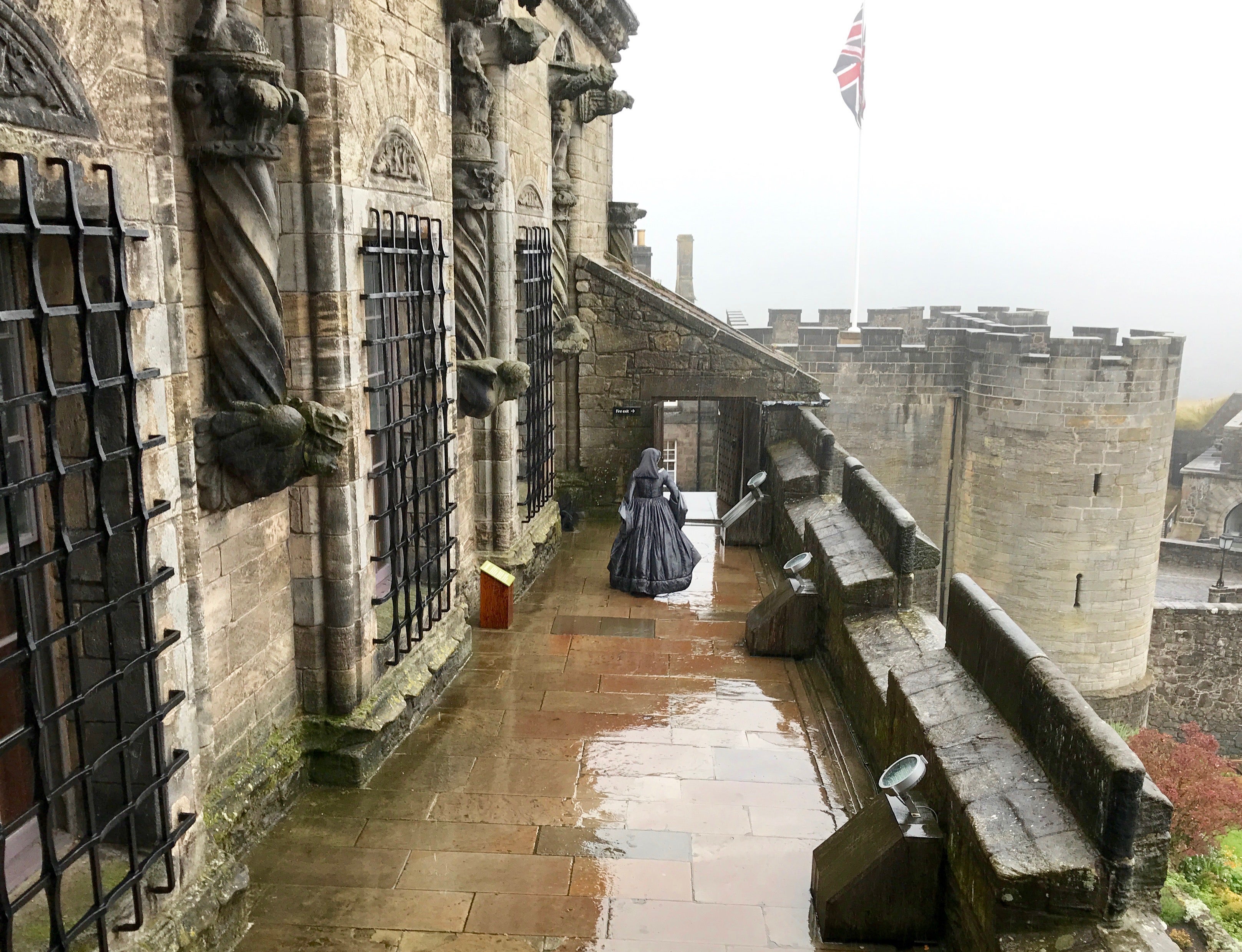 Dressed in period costume, this lady of Stirling Castle walks the ramparts in the rain.