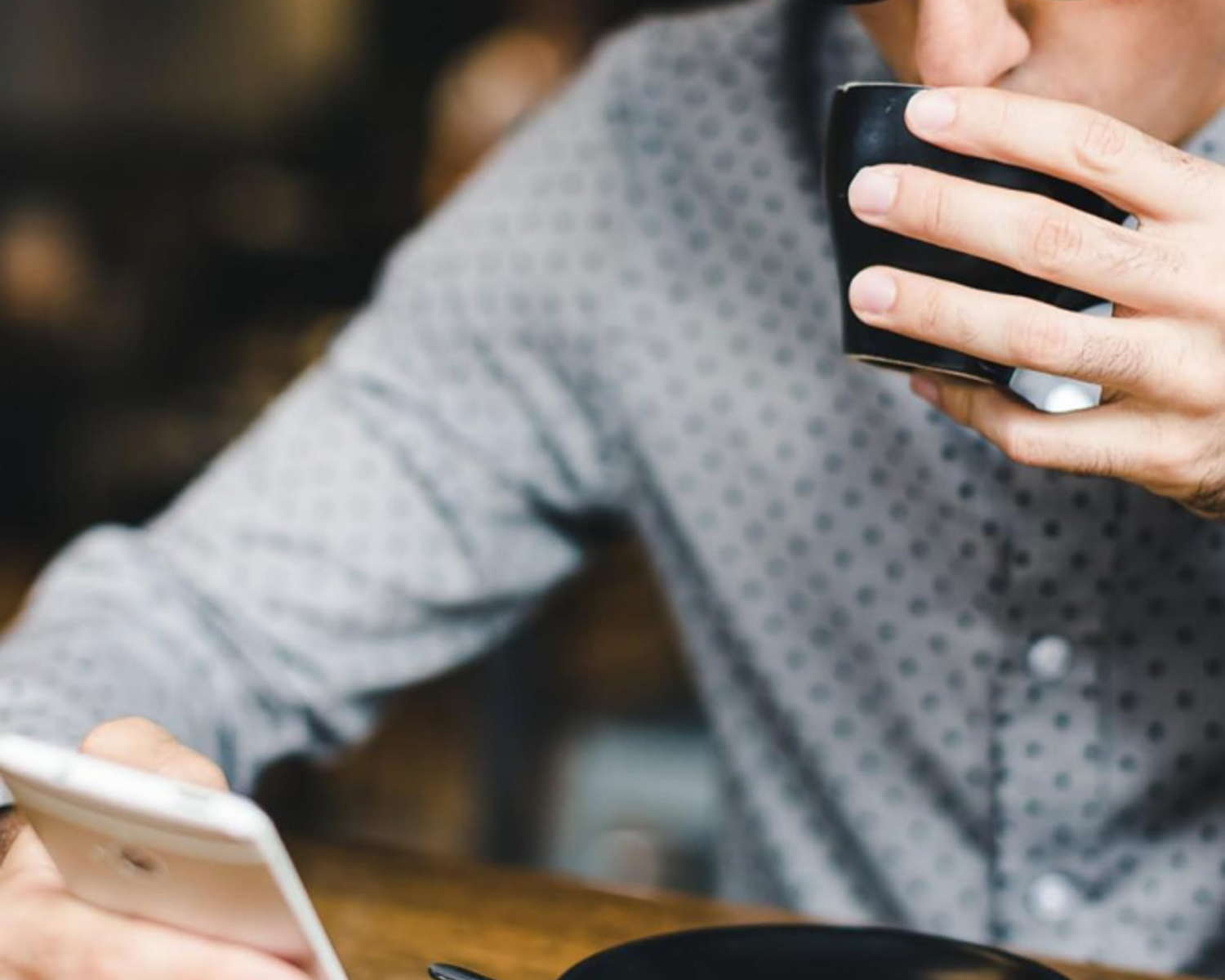 Man drinking coffee looking at phone