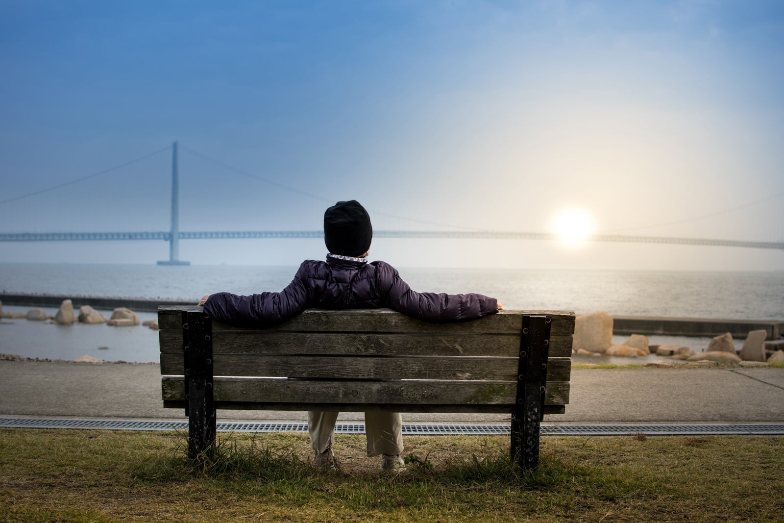 Sitting on park bench overlooking bridge over water