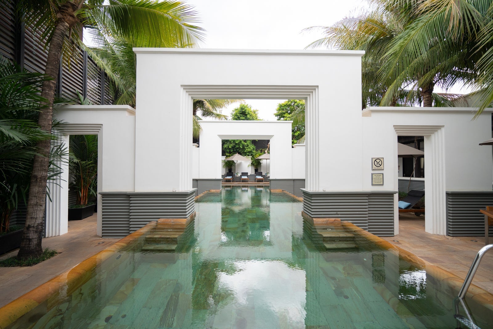 a hotel pool surrounded by palm trees and white walls