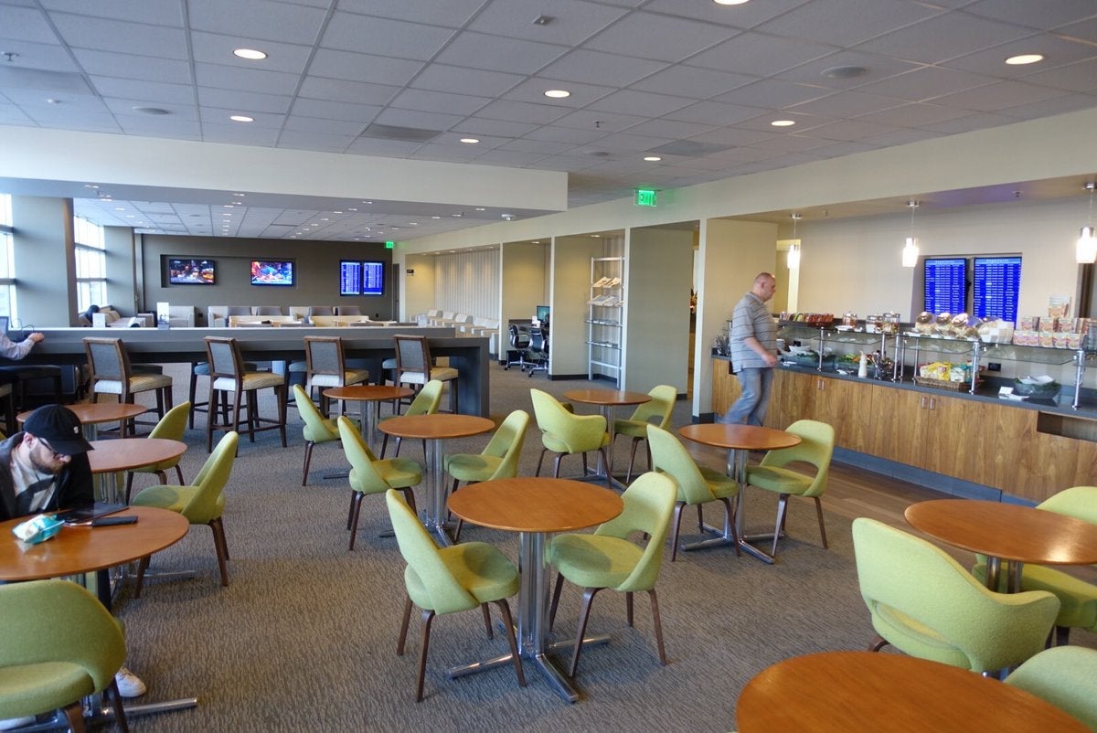 tables and chairs in a large seating area in an airport lounge