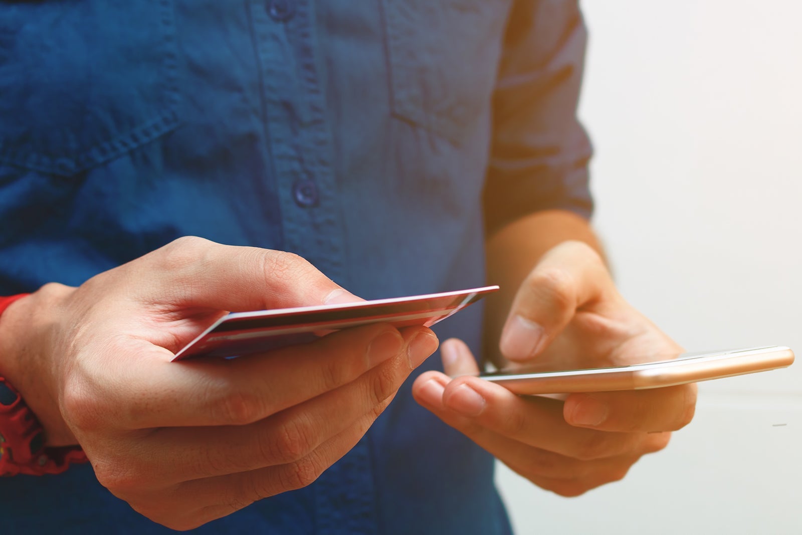 an unseen person holds a credit card while preparing to make a phone call
