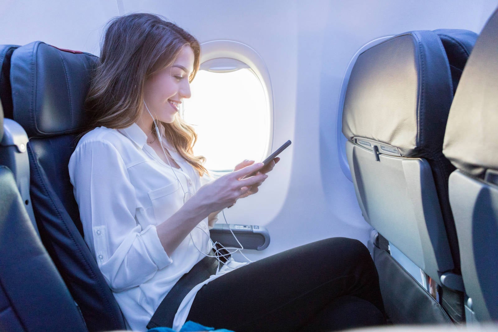 a woman uses her phone on a plane
