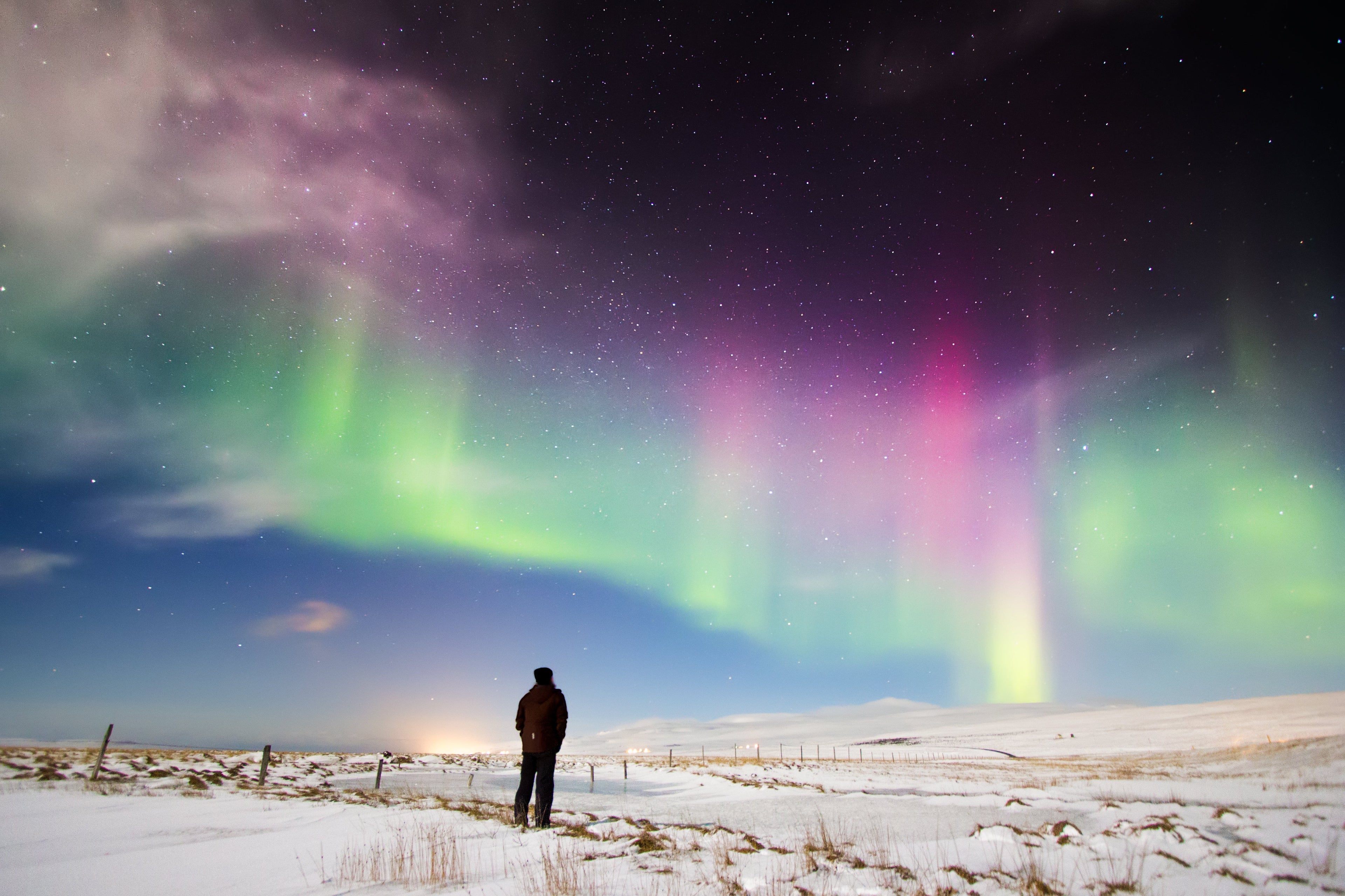 Snow covered ground with stars and Northern lights dancing in the sky.