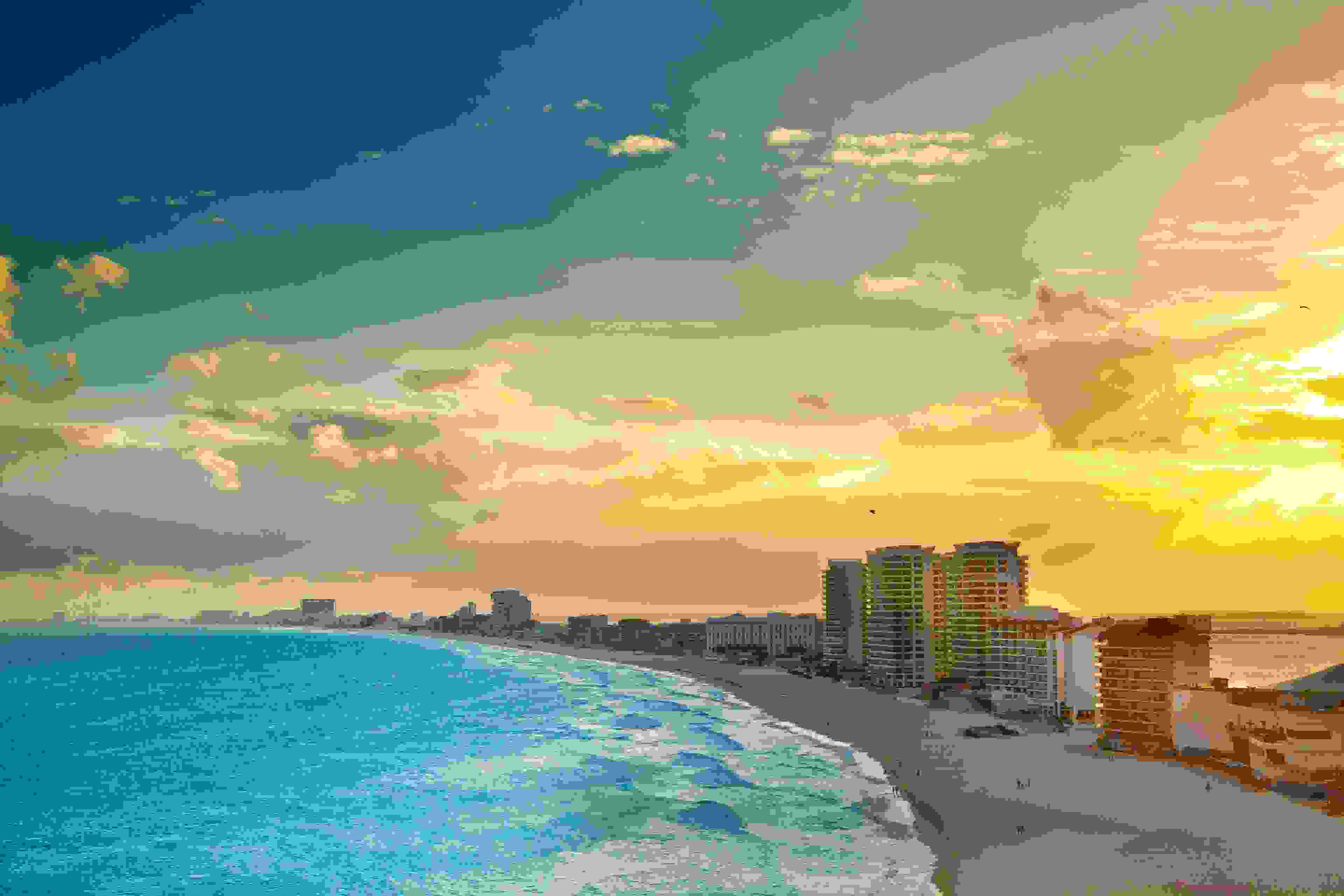 Subject: A panoramic view of the hotel district of Cancun at sunset. A popular tourist beach destination. The Yucatan Peninsula and the Riviera Maya in Mexico is a well developed vacation location with numerous hotels and entertainment districts. (Image by YinYang/iStock / Getty Images Plus)