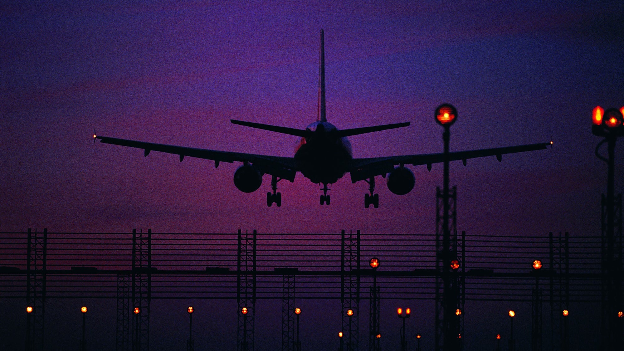 Silhouetted plane landing at night