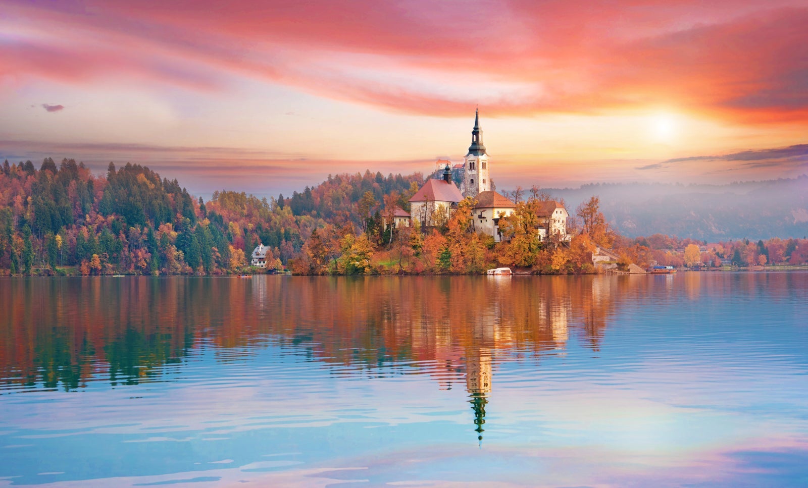 Lake Bled in Slovenia at sunset with colorful autumn trees and a castle 