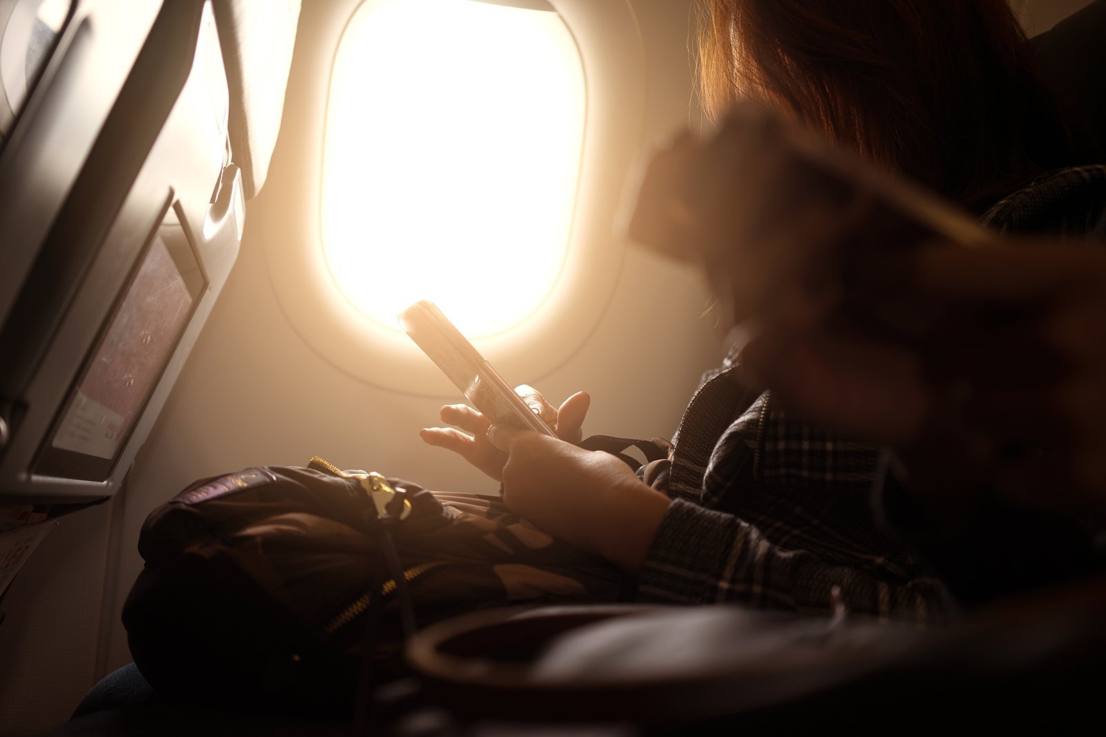 Asian man hand holding smart-phone start up working on board of airplane near window seat and wing