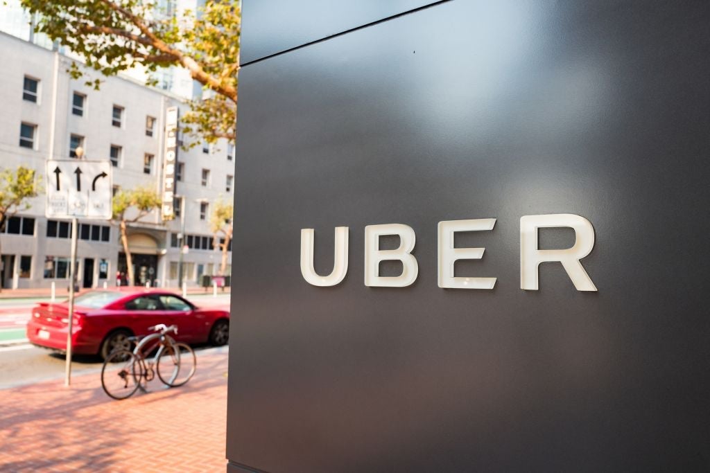Sign with logo at the headquarters of car-sharing technology company Uber in the South of Market (SoMa) neighborhood of San Francisco, California, with red vehicle visible in the background parked on Market Street, October 13, 2017. SoMa is known for having one of the highest concentrations of technology companies and startups of any region worldwide. (Photo by Smith Collection/Gado/Getty Images)