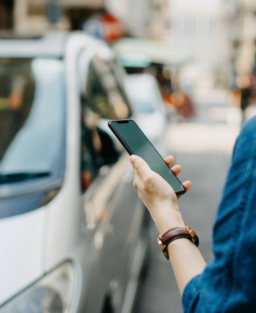 A person holds a phone while ordering from a rideshare app