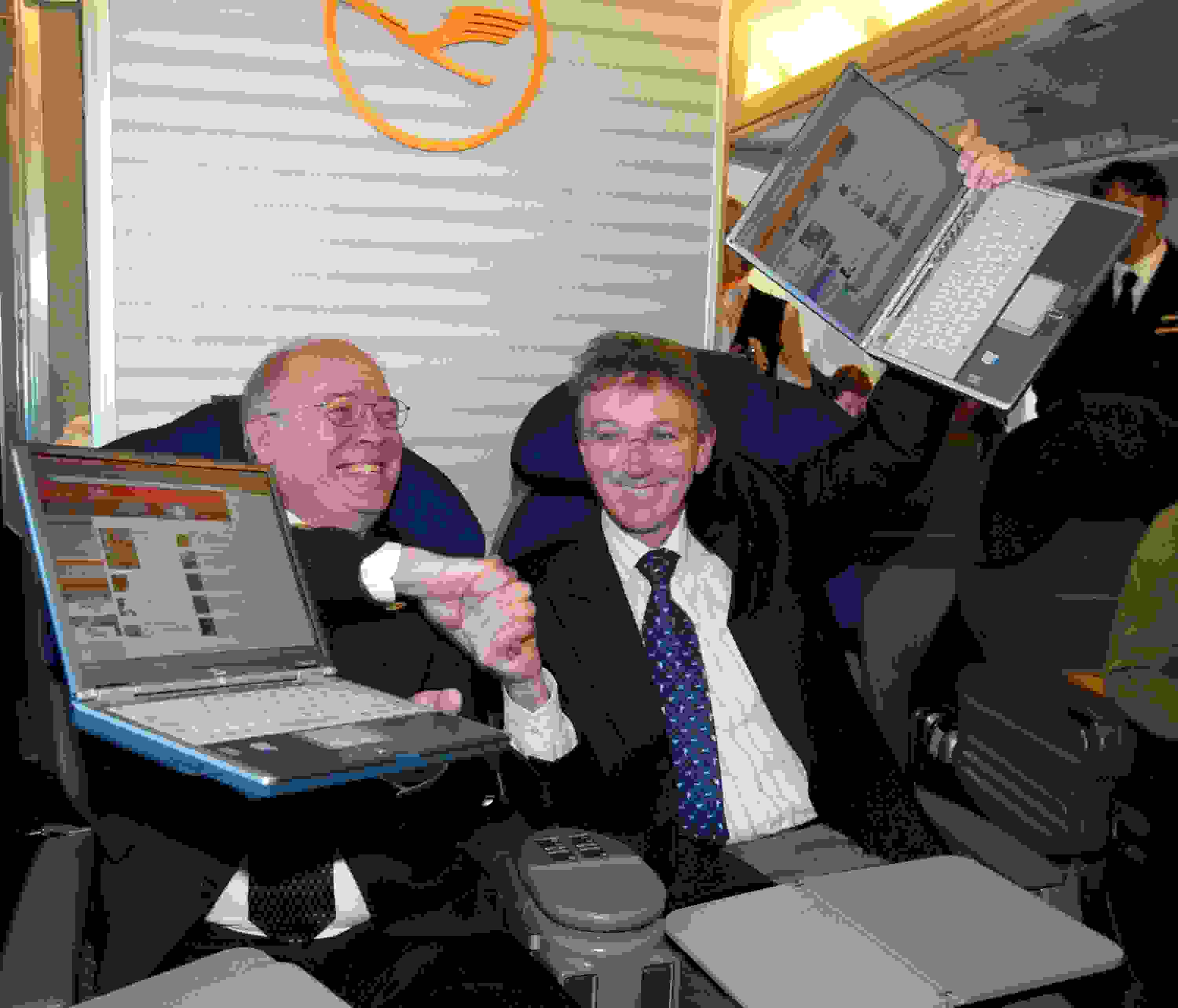 Scott Carson, (L) President of Connexion by Boeing, and Wolfgang Mayrhuber, CEO of Lufthansa, celebrate as they surf the web on a laptop computers hooked up to the Internet on Lufthansa flight 418 from Frankfurt to Washington, D.C., January 15, 2003. The flight initiated a new communications era in the history of air travel called FlyNet. With FlyNet, Lufthansa offers the fastest and most powerful Internet access ever installed onboard a commercial airliner. The Internet access service is based on a cooperation between Connexion by Boeing and Lufthansa which began in mid-June 2001. (Photo by Jeff Christensen/WireImage)