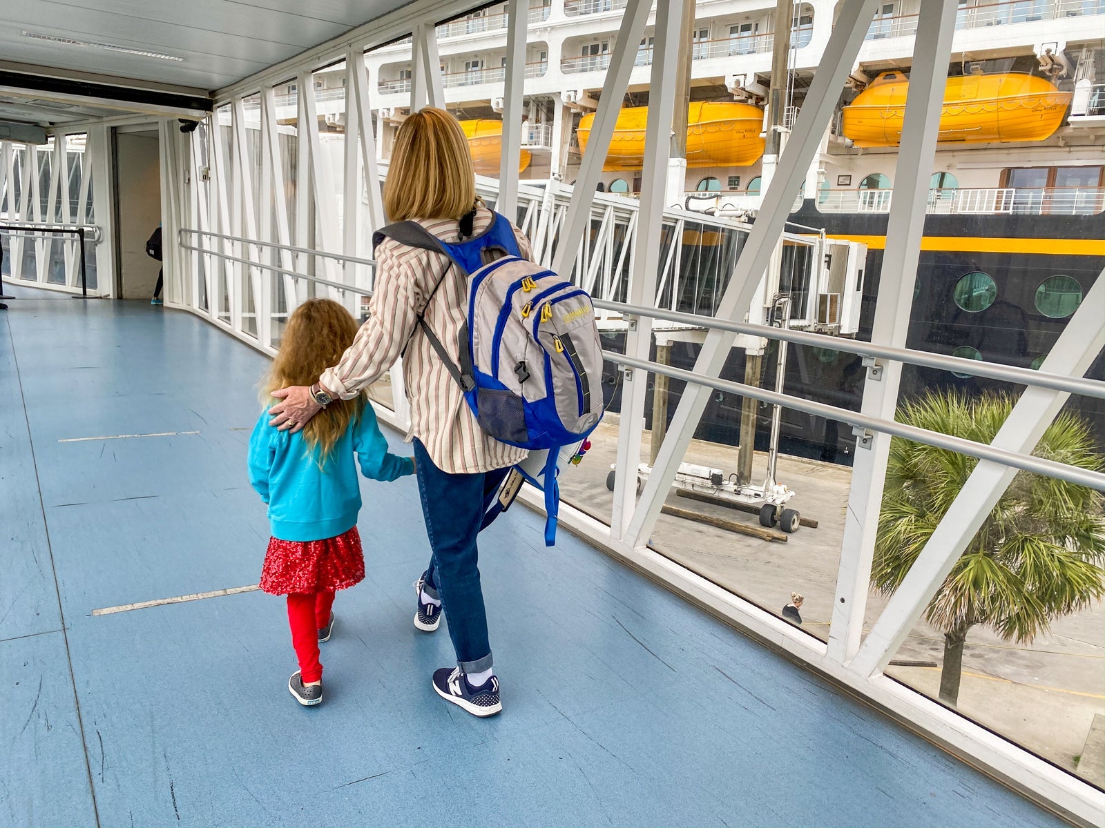 A mother guides her child down the gangway of a cruise ship