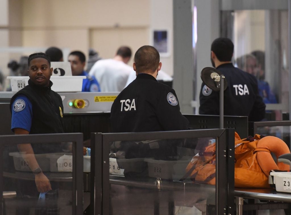 Transportation Security Administration officers (TSA) stand screen passengers at the departure area of the Los Angeles International Airport in Los Angeles, California, on 5 January, 2019. - TSA staff are taking sick leave in record numbers since the partial government shutdown forced them to work without pay from December 22, 2018. Shortly after the new Congress was sworn in on January 4, 2019, the House approved legislation to fund homeland security operations until February 8 and several other agencies through September -- but no money for a wall. Trump has said he would veto any bill that does not include funding for the barrier and the Republican-run Senate has said it would not consider anything that does not pass muster with the president. (Photo by Mark RALSTON / AFP) (Photo credit should read MARK RALSTON/AFP/Getty Images)