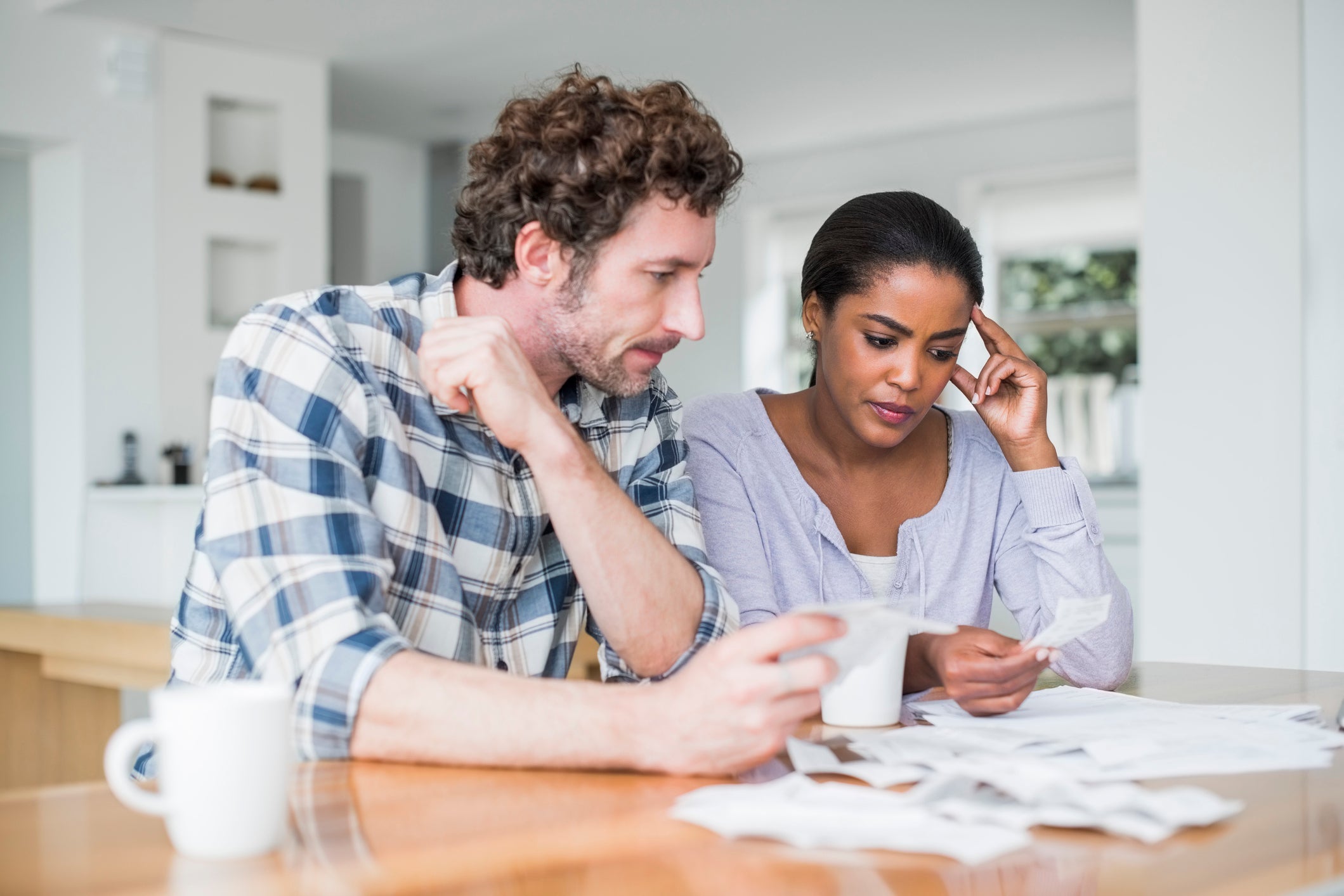 Multi-ethnic couple reading bills at home.