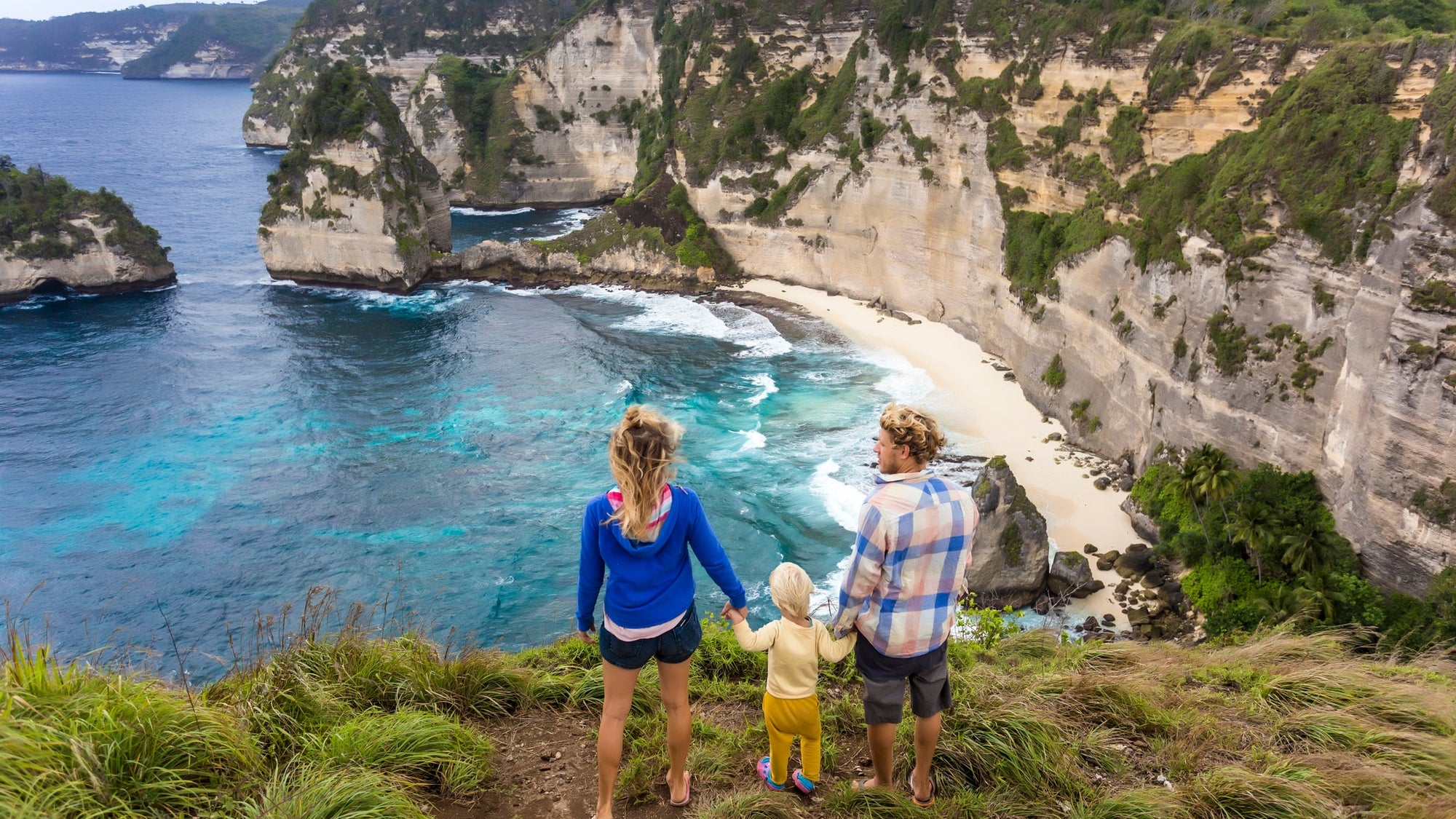 Family on vacations looking at view of coastline with cliffs, Nusa Penida, Bali, Indonesia