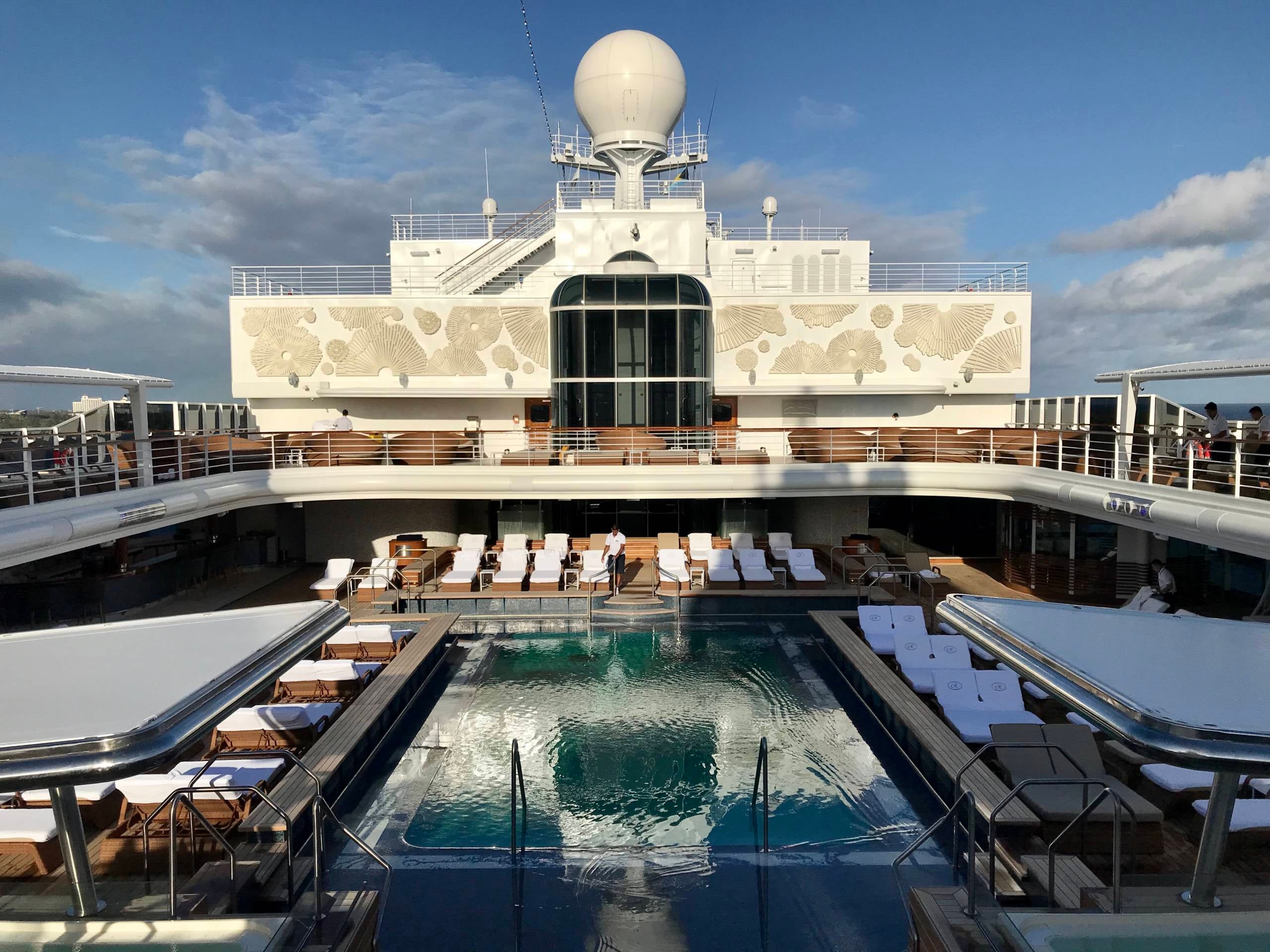 The pool deck on a luxury cruise ship surrouned by lounge chairs