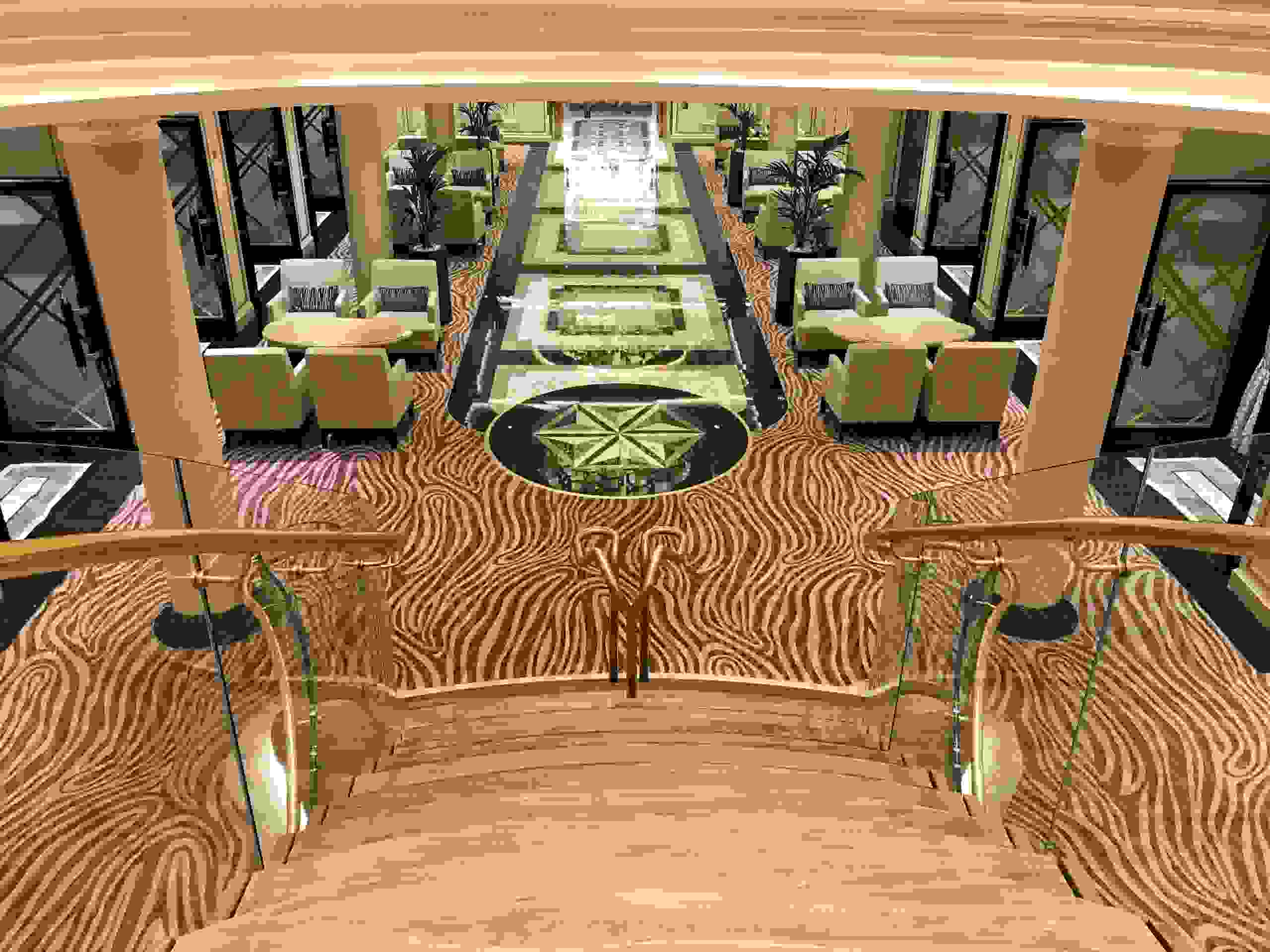 The grand staircase at the center of Seven Seas Splendor's atrium area descends toward an inlaid marble pathway that leads to the main Compass Rose restaurant. (Photo by Gene Sloan/The Points Guy)