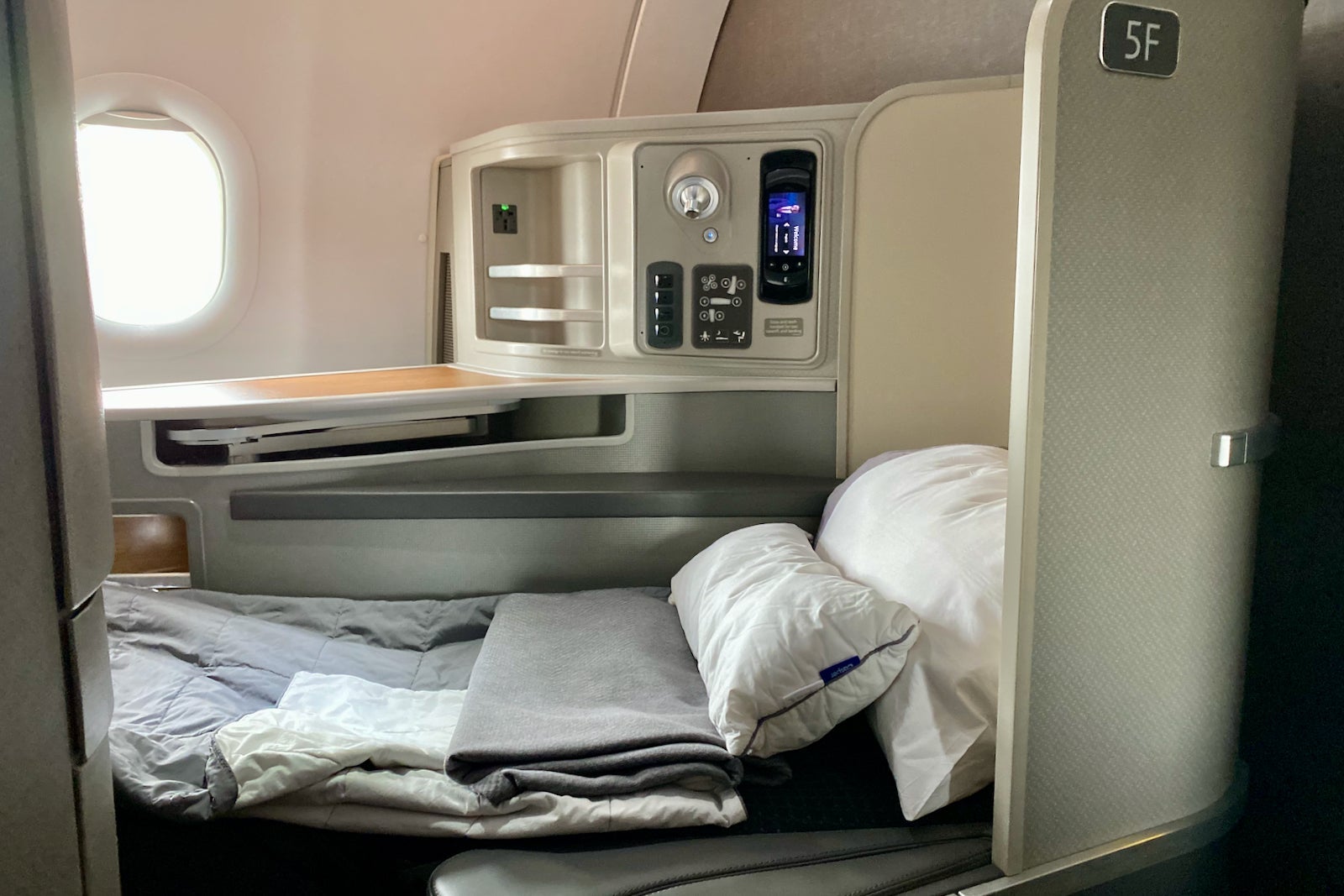 A first-class seat in the bed position with blanket and pillow