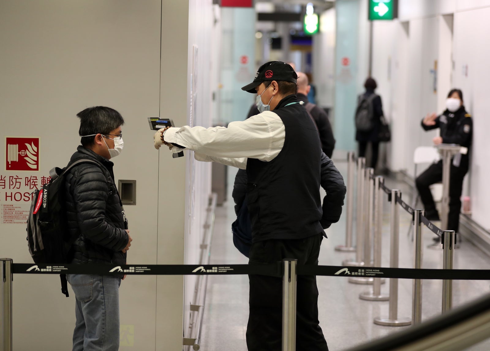 A masked worker checking his colleagues temperature before entering staff channel at the Hong Kong international Airport. (Photo by May James/SOPA Images/LightRocket/Getty Images)