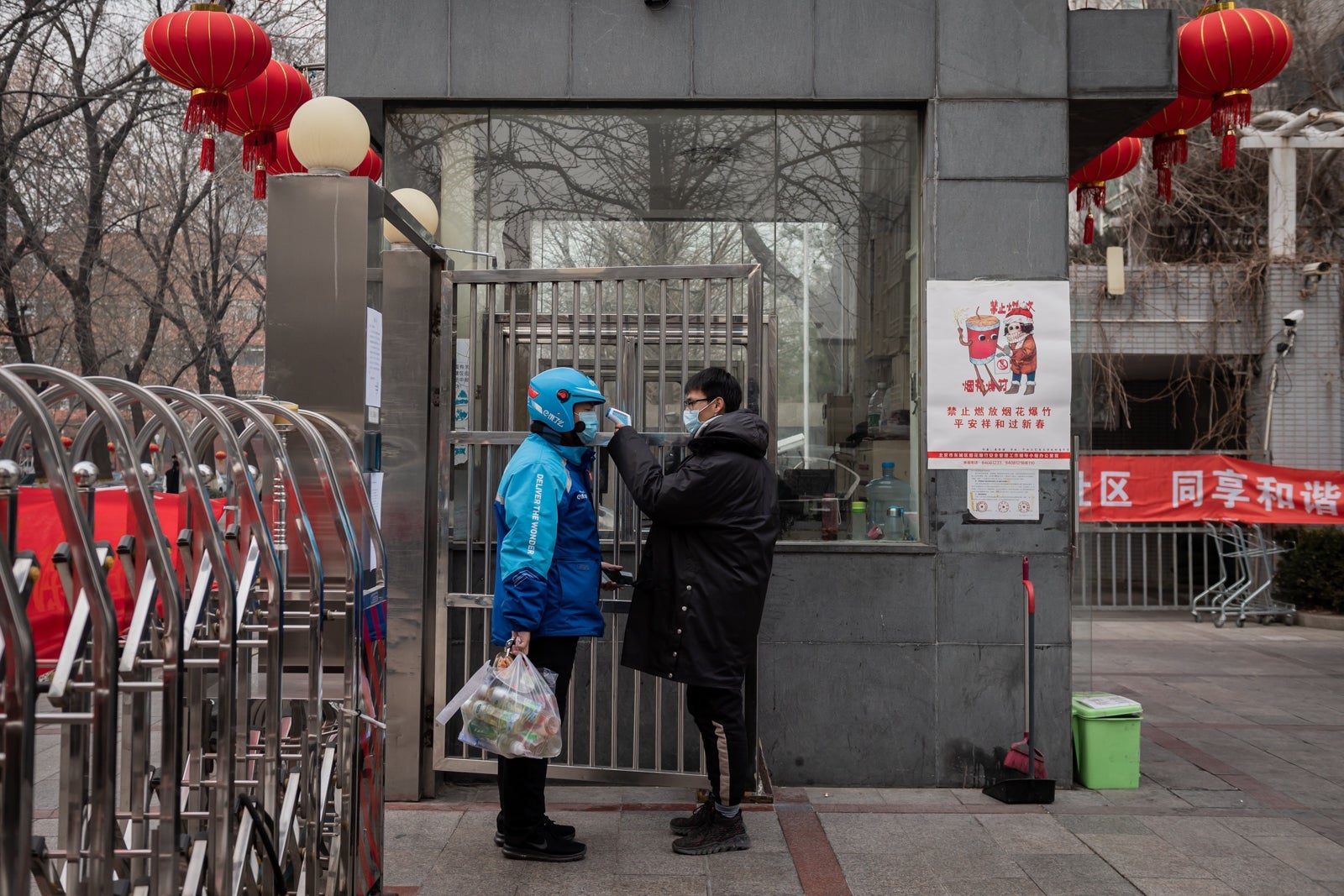 A security guard checks the temperature of a food delivery worker. (Photo by NICOLAS ASFOURI/AFP/Getty Images)