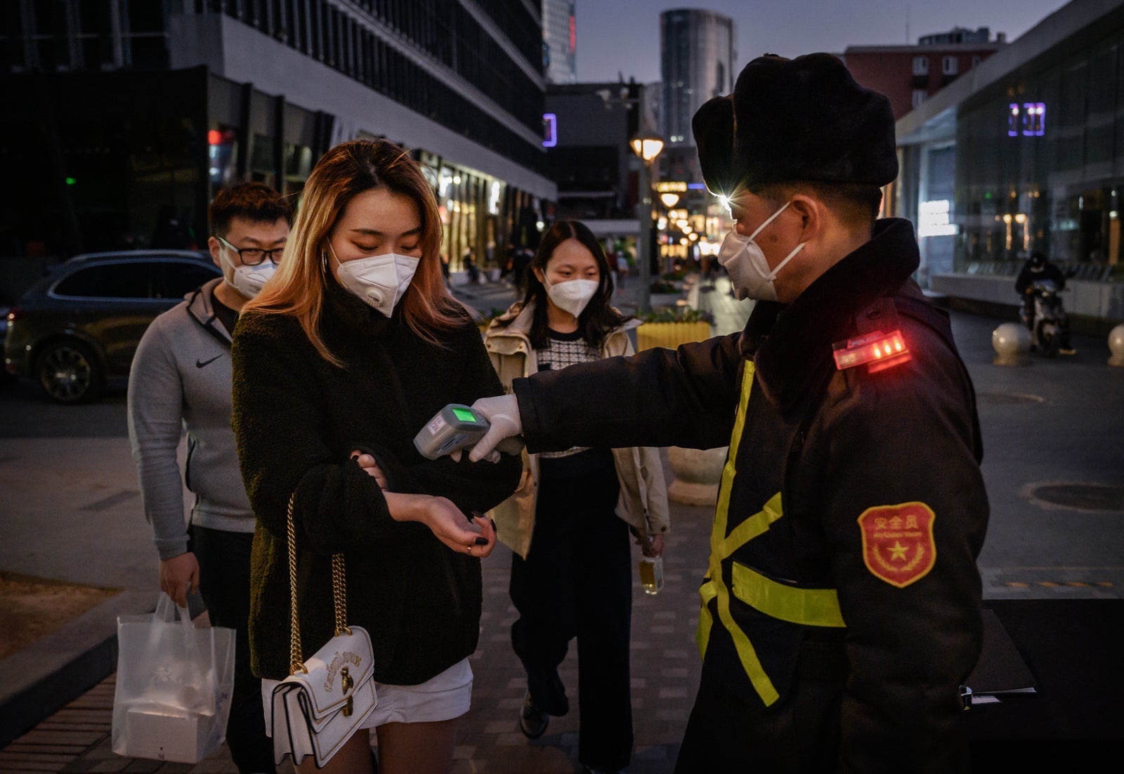 A Chinese woman wears a protective mask as she has her temperature checked by a security guard. (Photo by Kevin Frayer/Getty Images)