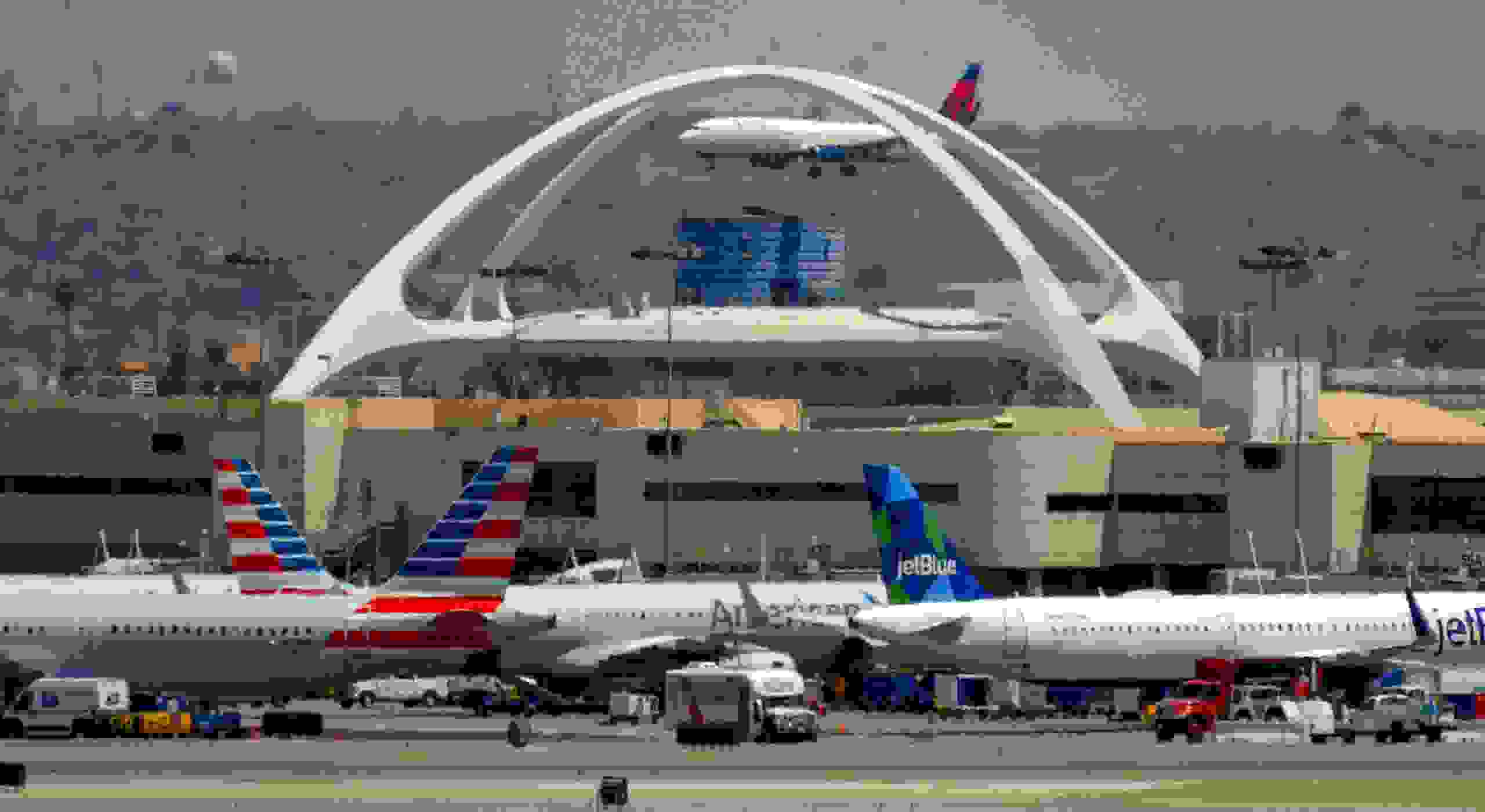 LOS ANGELES, CA - AUGUST 03: A planes sit at their gates, a Delta airline lands behind the theme building at LAX in Los Angeles on Thursday, August 3, 2017. The EPA says aircrafts account for a tenth of the nation's transportation related greenhouse gasses. And there's an international effort afoot to cut down pollution created in the air. (Photo by Scott Varley/Digital First Media/Torrance Daily Breeze via Getty Images)
