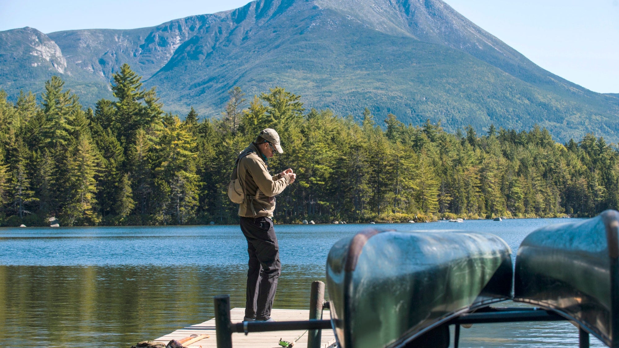 Fly Fisherman getting his gear ready on the dock at Kidney Pond in Baxter State Park, Maine