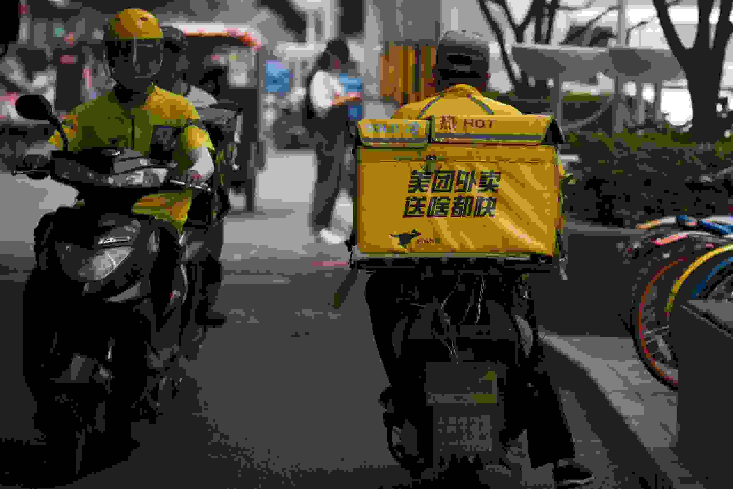 Two Meituan food deliverymen ride their scooters in Beijing on June 26, 2018. - Chinese online services giant Meituan-Dianping filed for an initial public offering in Hong Kong on June 25 in what could become the biggest IPO of the year. (Photo by WANG ZHAO / AFP) (Photo credit should read WANG ZHAO/AFP via Getty Images)