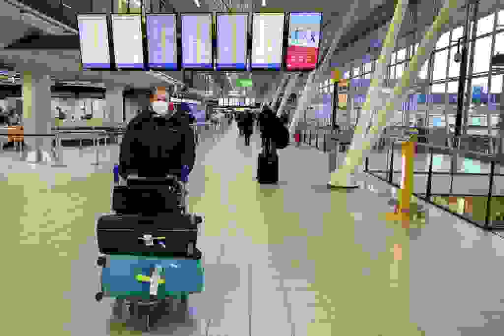 A traveler wearing a protective face masks pushes his luggage on a cart in Amsterdam Schiphol airport on February 2, 2020. - A number of airlines, including Netherlands' KLM are halting or reducing flights to China as the country struggles to contain the spread of the deadly novel coronavirus, which death toll soared to 304 with the first fatality outside the country reported in the Philippines. (Photo by Evert ELZINGA / ANP / AFP) / Netherlands OUT (Photo by EVERT ELZINGA/ANP/AFP via Getty Images)