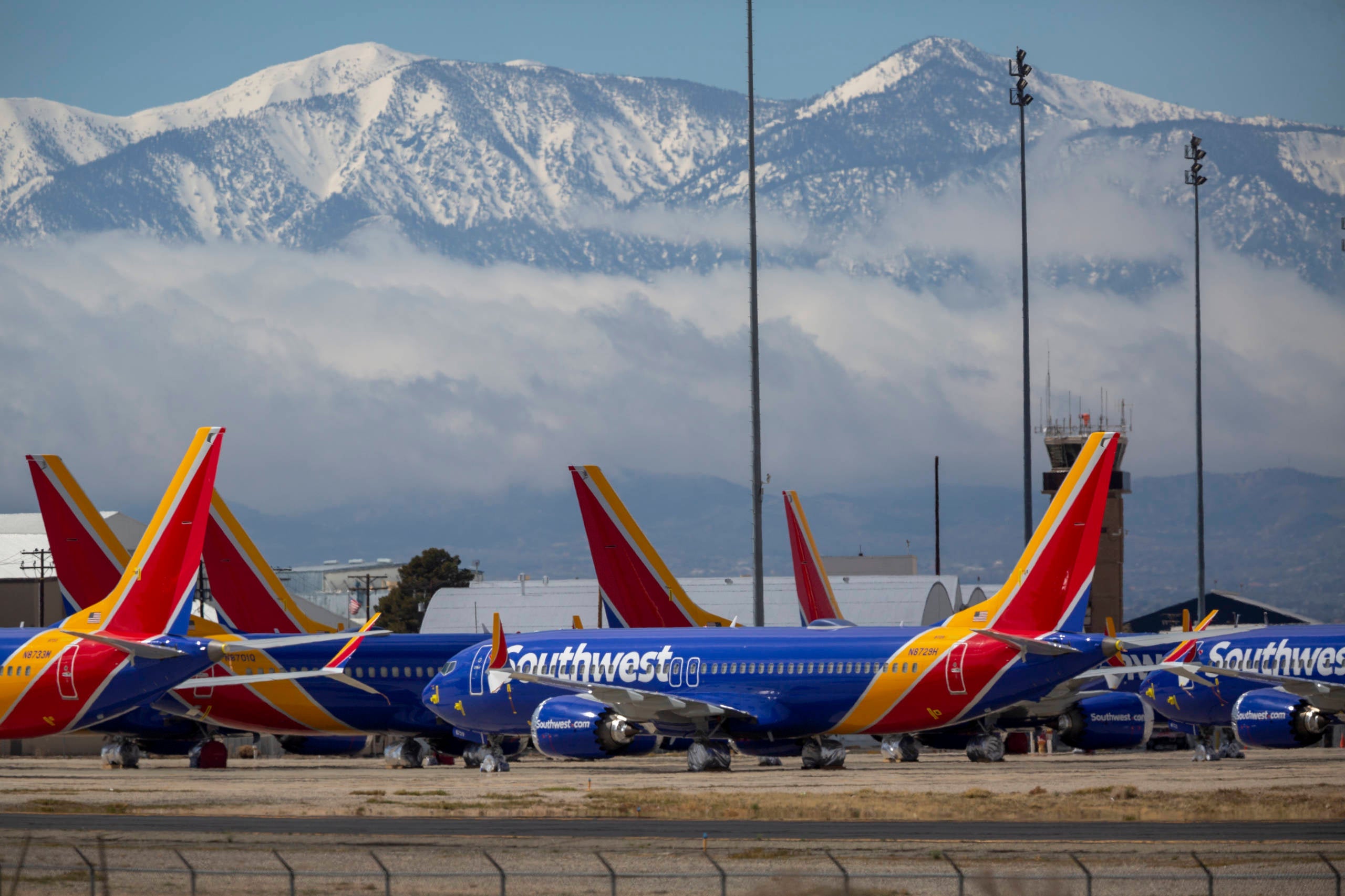 Multiple Southwest Airlines planes on the tarmac with snow-capped mountains in the background
