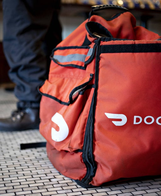 a DoorDash food delivery bag sits on the floor near an unseen person's feet