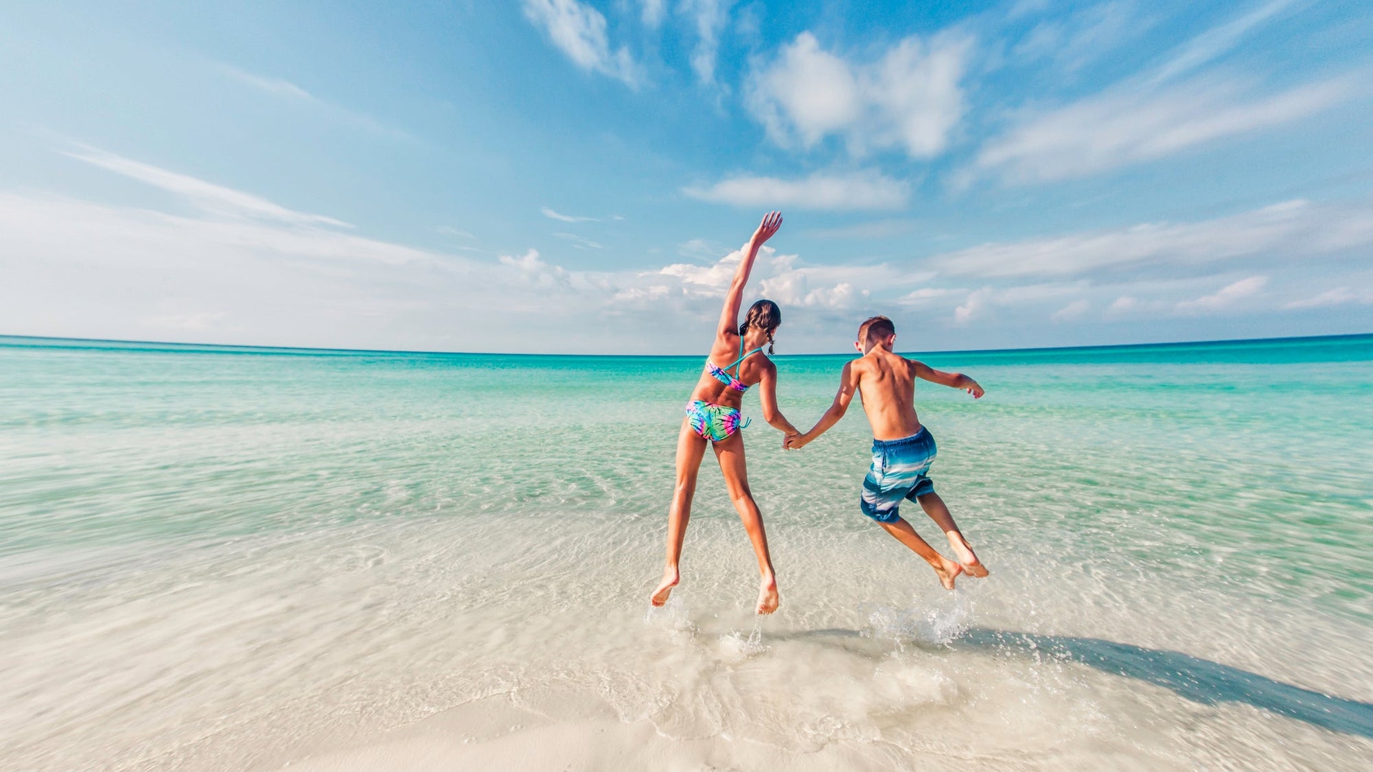 boy and girl jumping in the surf of the Gulf of Mexico