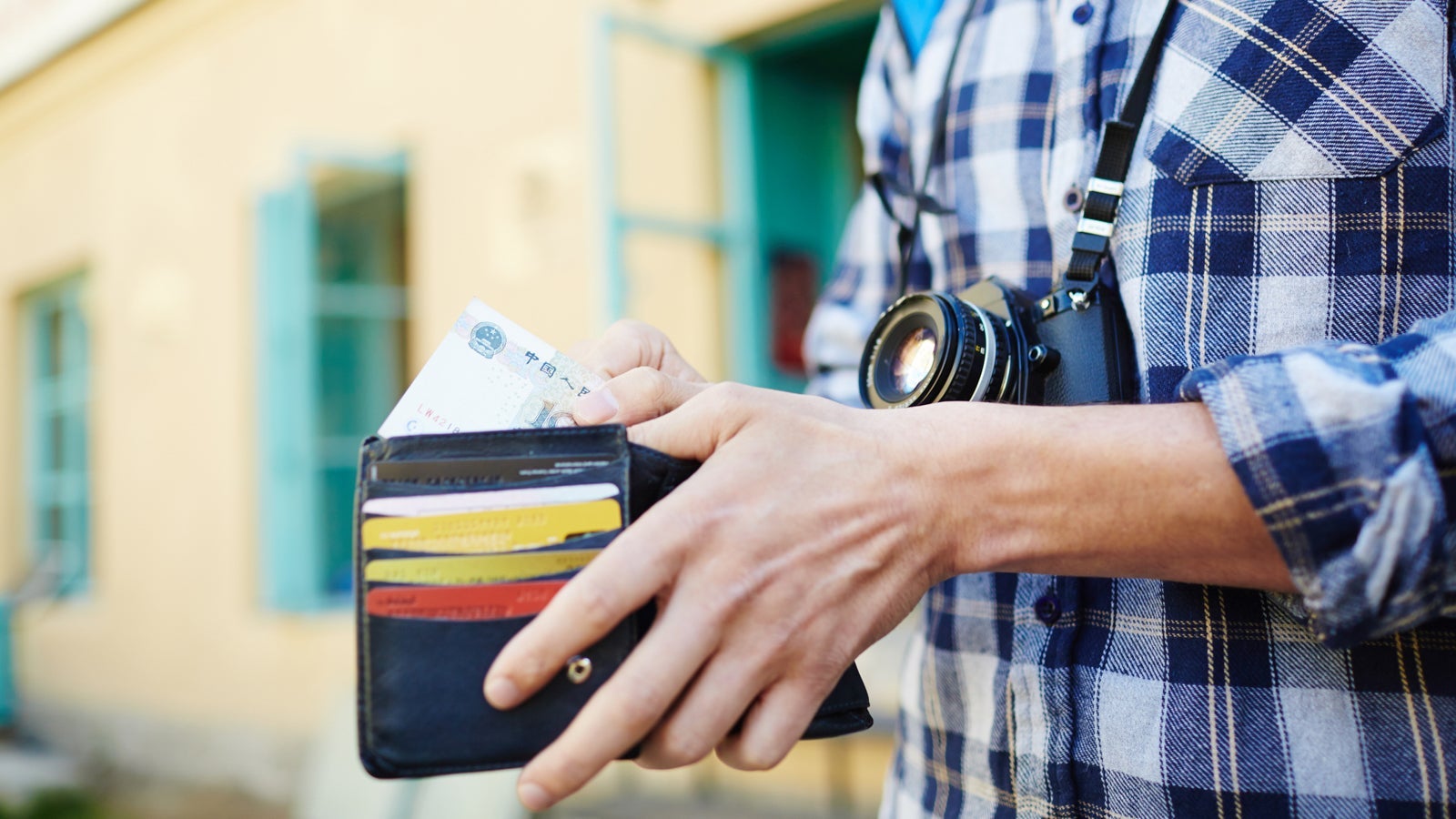 Closeup image of young tourist putting money in wallet, saving money for vacation trips