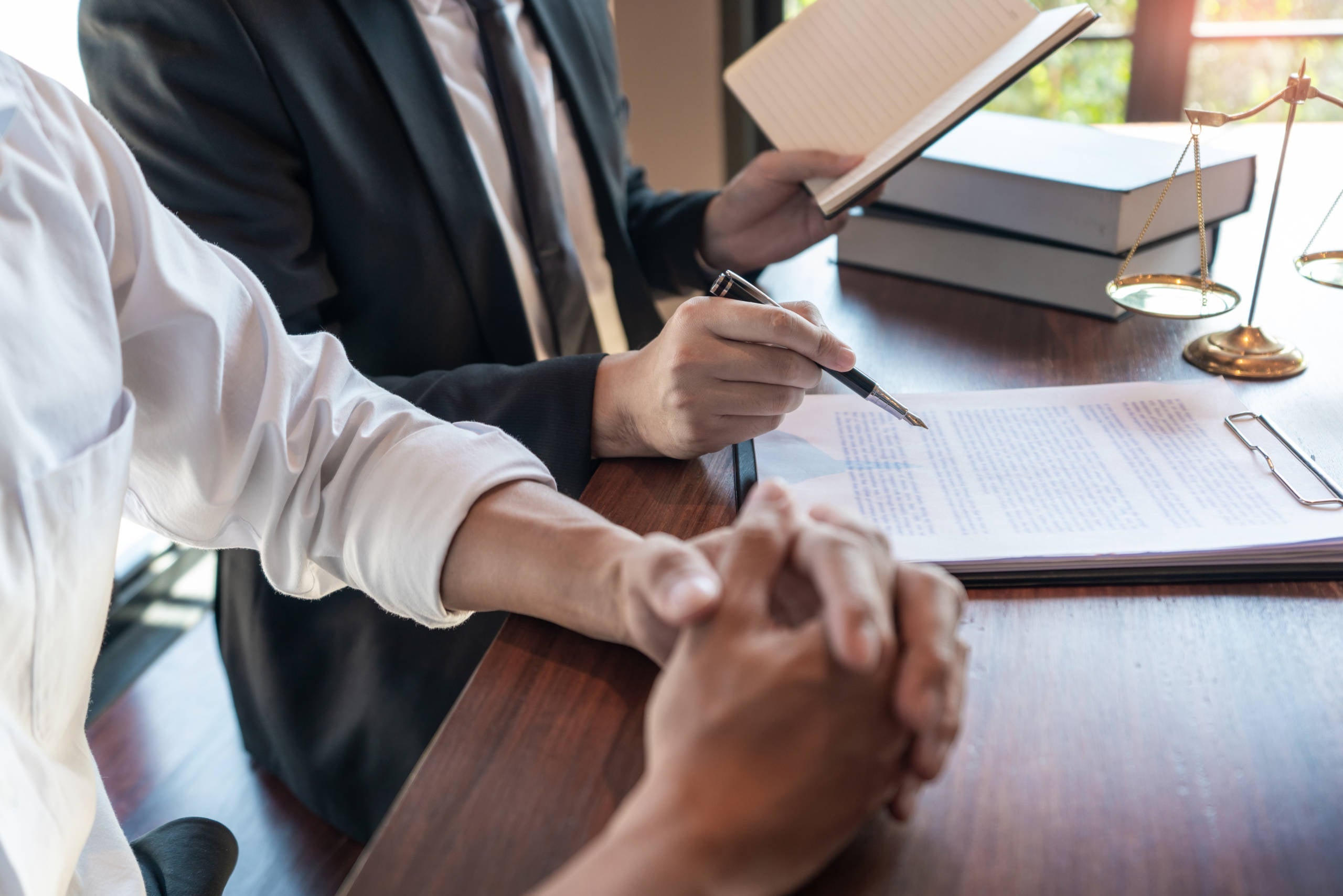 2 unseen people review legal documents together