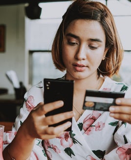A person holding a credit card while shopping online from a smartphone
