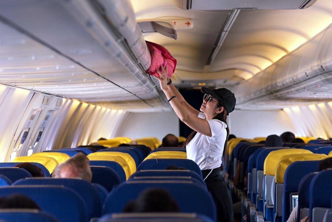 Person Putting Luggage into Overhead Bin