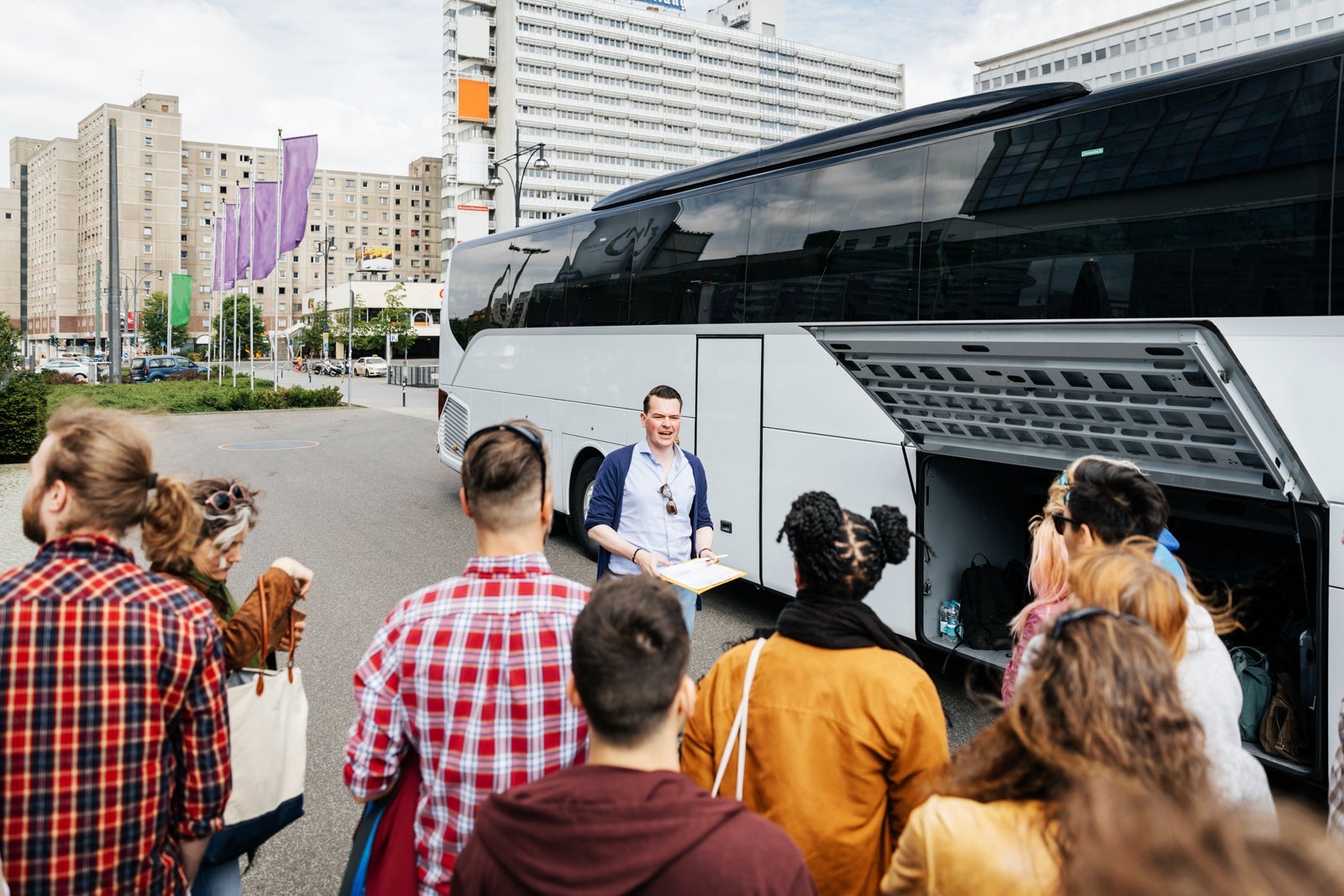 Tour guide talking to tour group outside bus