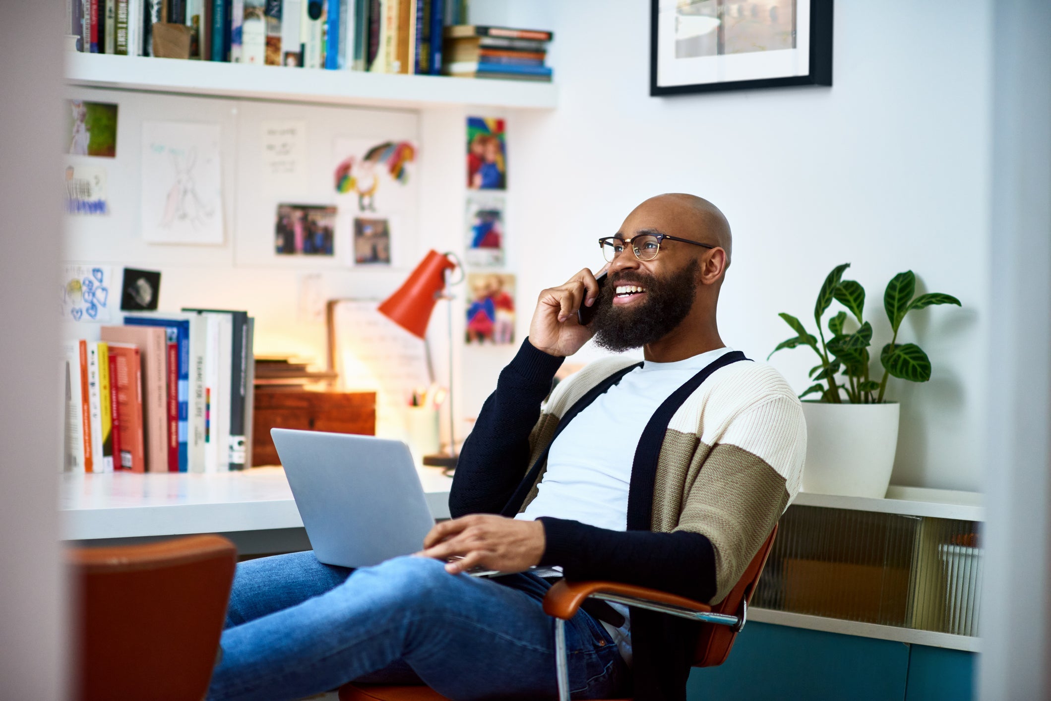 Happy man talking on his cell phone with his laptop on his lap
