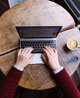 Directly above view of a man working on laptop in coffee shop, personal perspective view