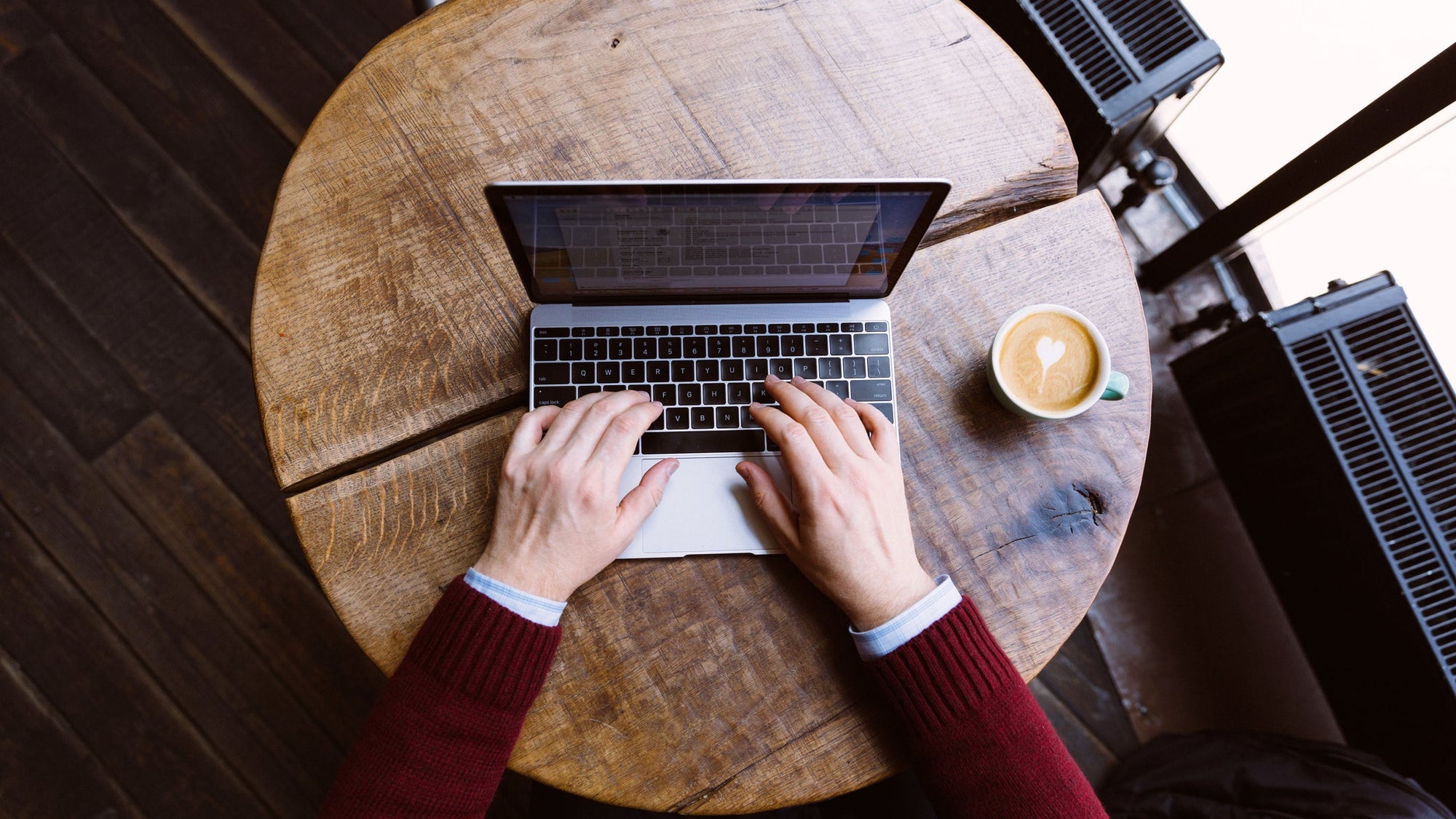 Directly above view of a man working on laptop in coffee shop, personal perspective view