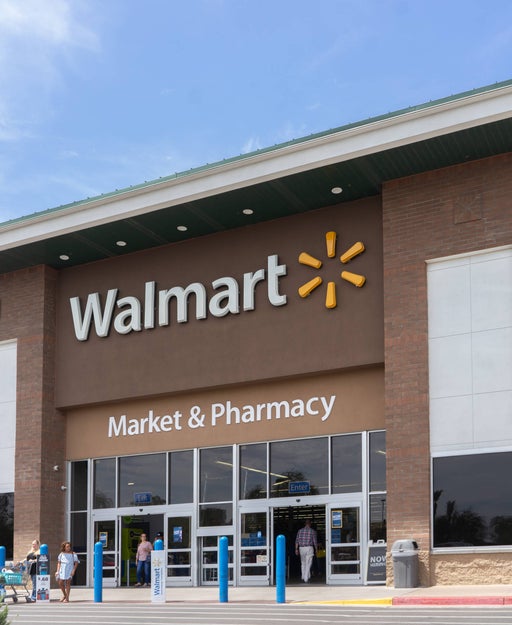 Shoppers enter and exit the front of a Walmart building.