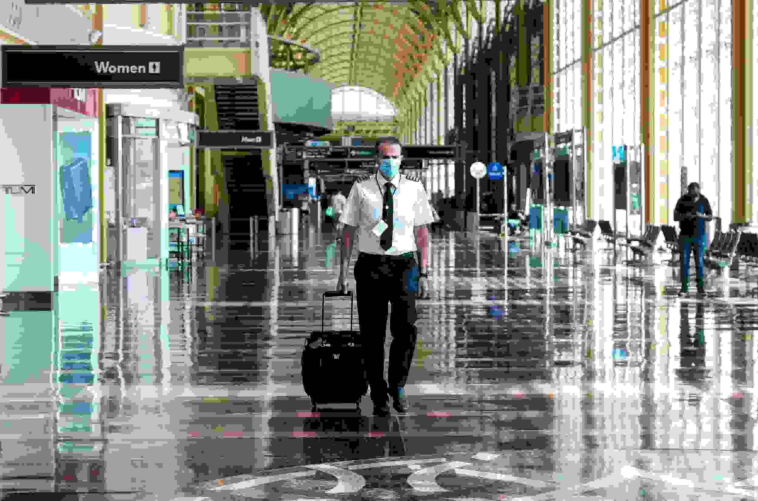 ARLINGTON, VA - JULY 22: A pilot walks through the terminal at the Ronald Reagan National Airport on July 22, 2020 in Arlington, Virginia. During the COVID-19 pandemic, all Delta Airlines employees and passengers are required to wear facemasks while onboard a Delta plane. (Photo by Michael A. McCoy/Getty Images)